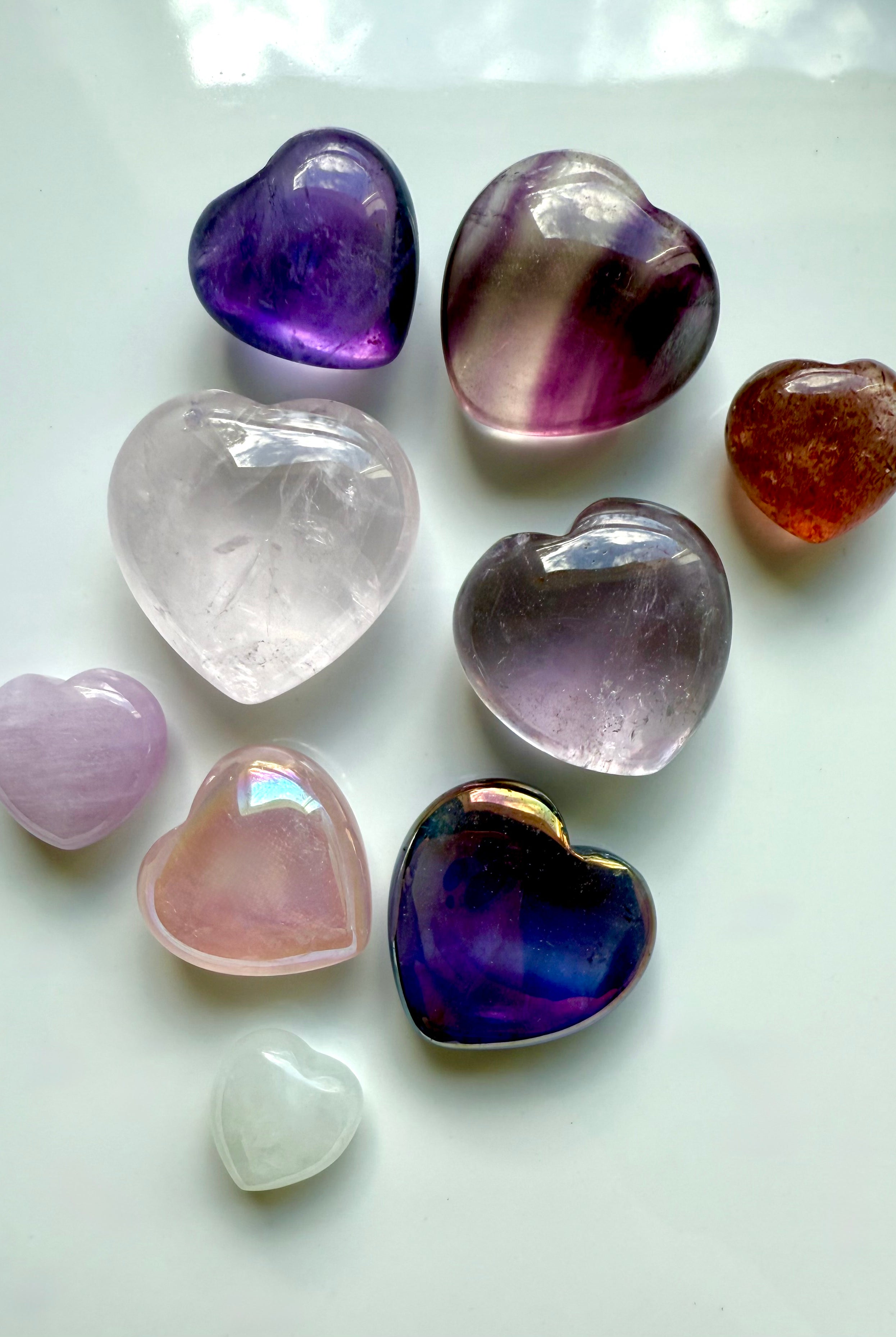 Close-up of vibrant pink and purple mini crystal hearts on white, showing aura iridescence, size, and quality.