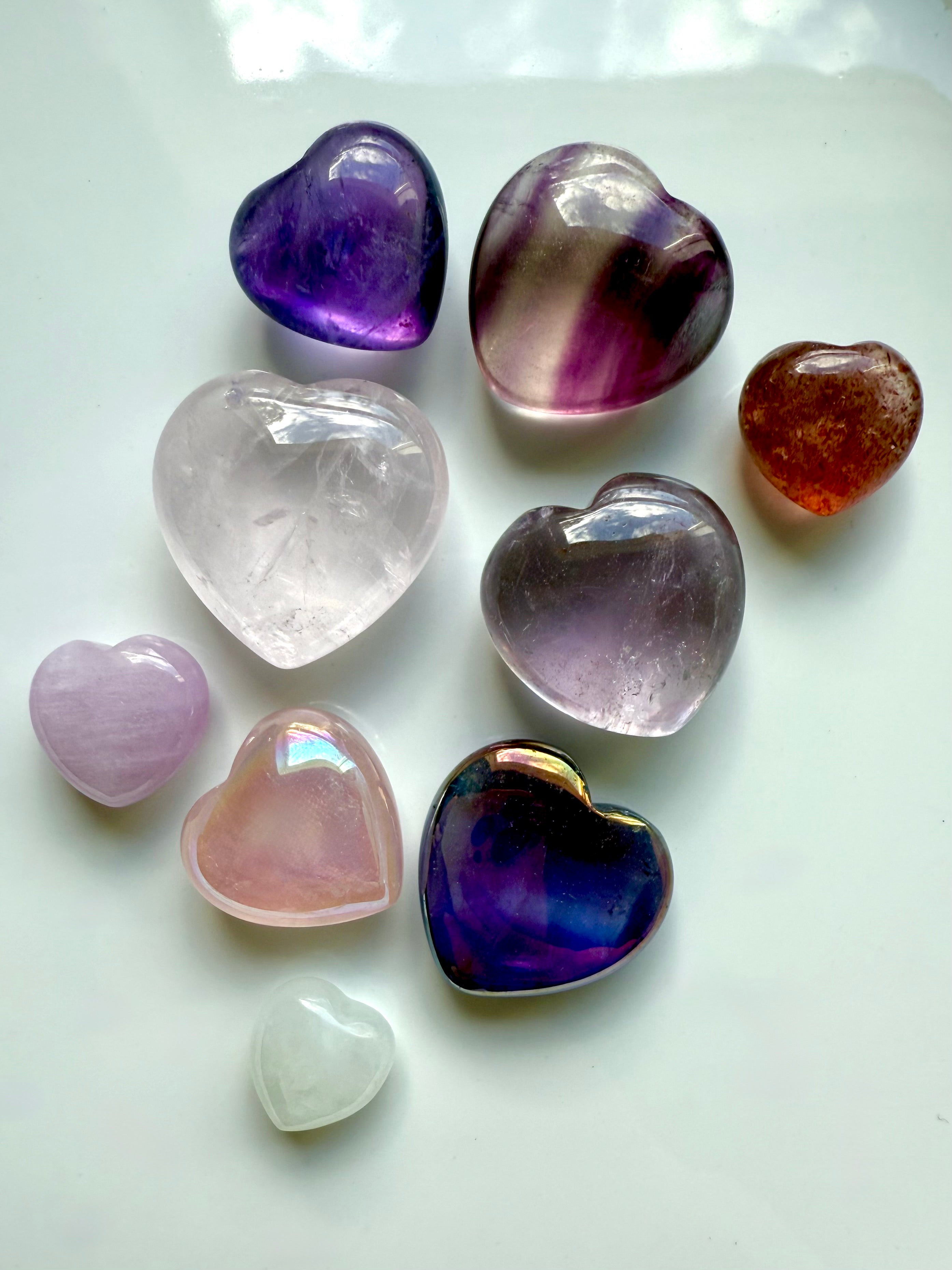 Close-up of vibrant pink and purple mini crystal hearts on white, showing aura iridescence, size, and quality.