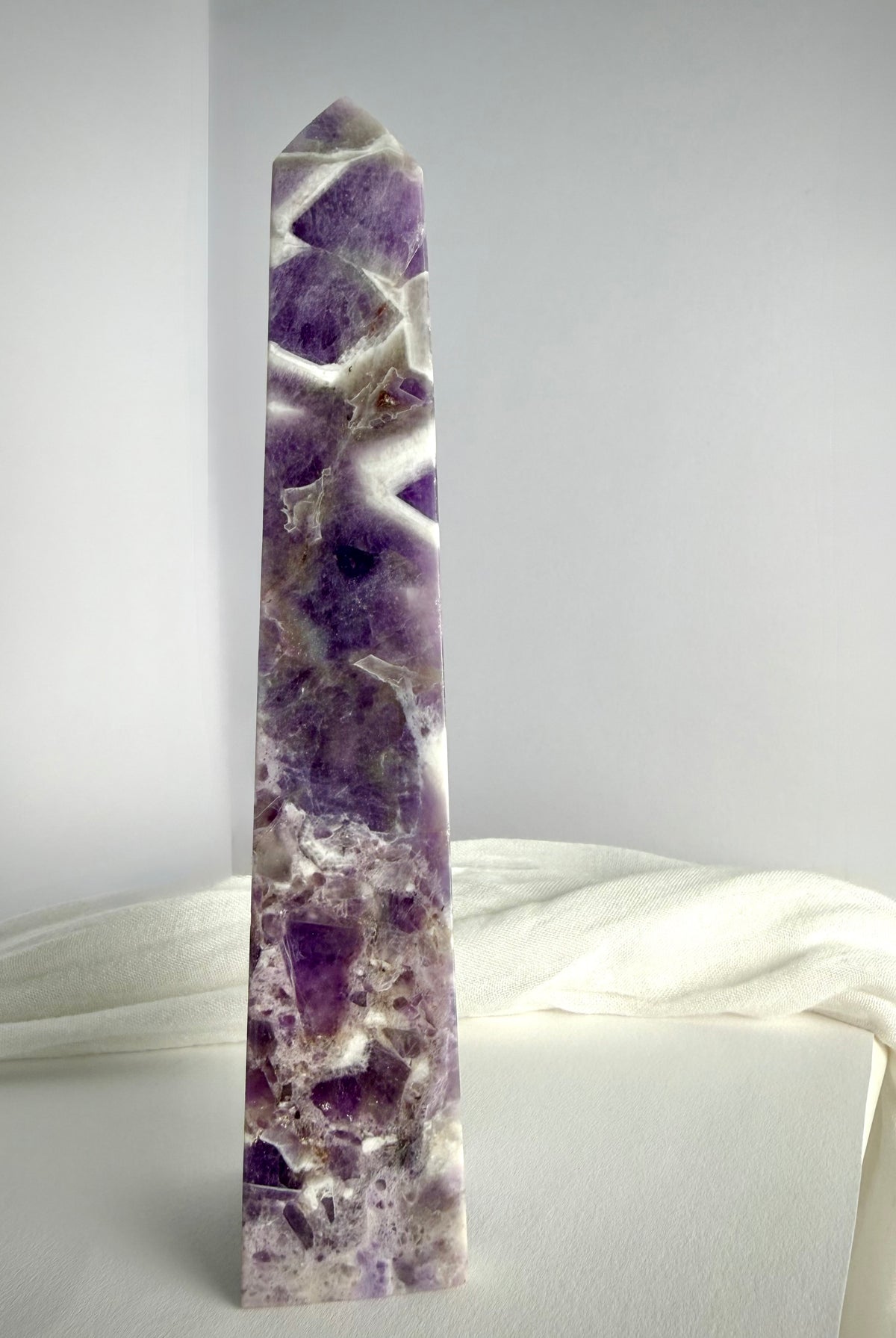 Polished Chevron Amethyst tower standing upright, featuring dramatic purple crystal formations and contrasting white quartz inclusions