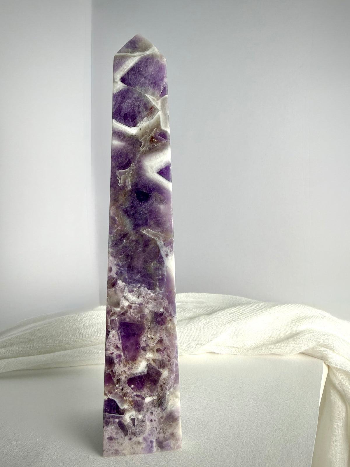 Polished Chevron Amethyst tower standing upright, featuring dramatic purple crystal formations and contrasting white quartz inclusions
