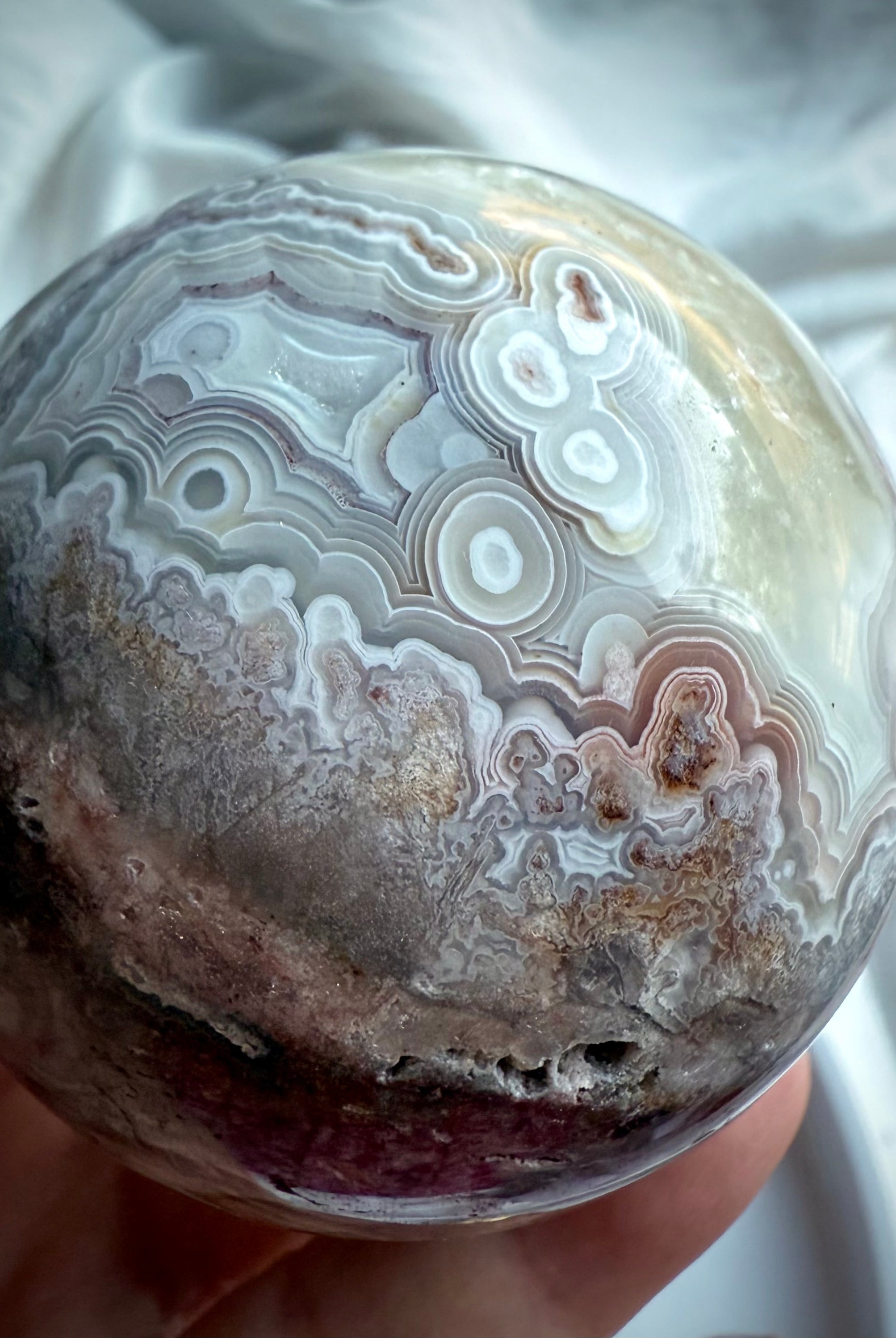 Close-up of intricate pink, lilac, and ivory agate banding with orbicular patterns on polished crystal sphere