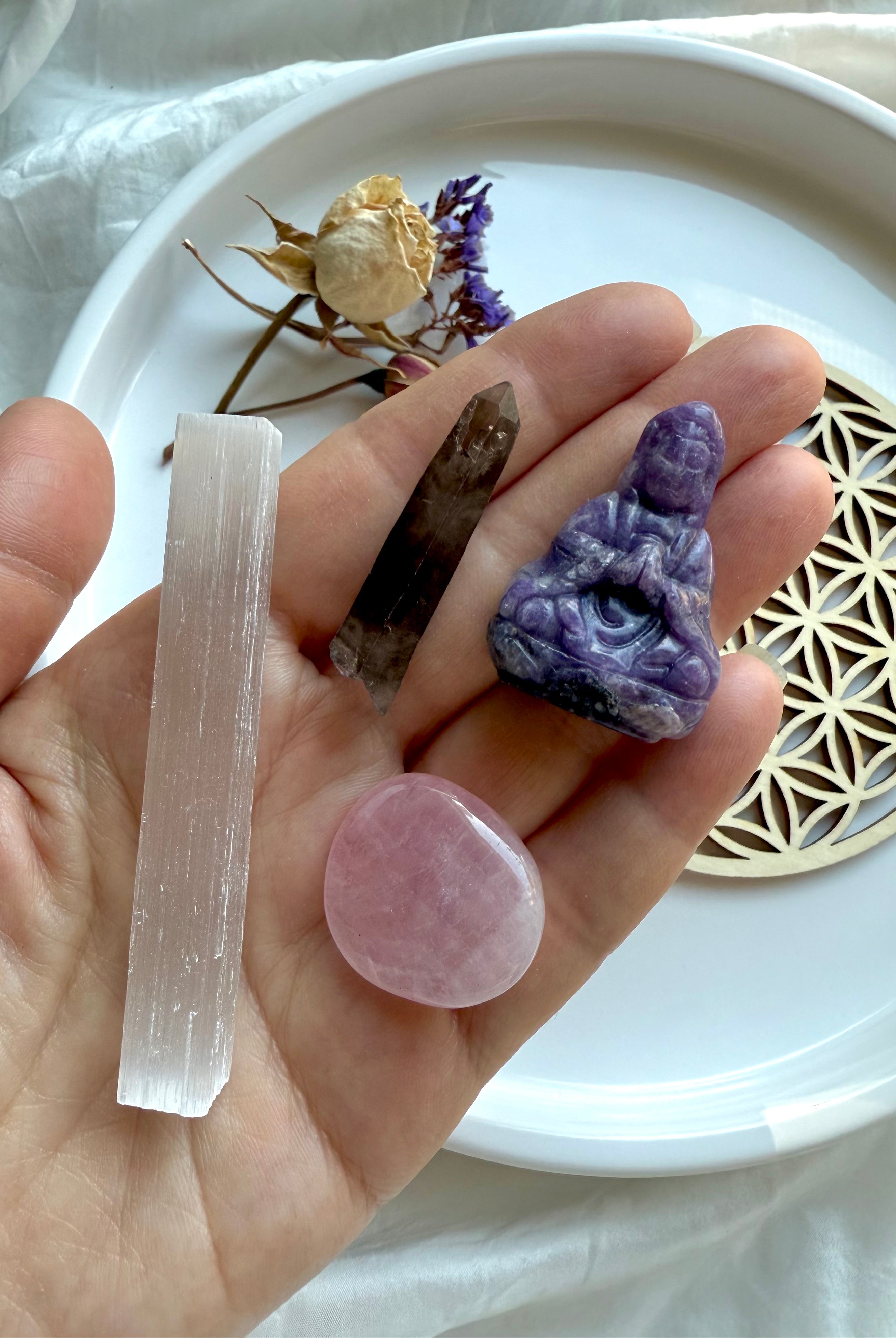 Hand holding Lepidolite Quan Yin, rose quartz, smoky quartz + selenite – components of the Quan Yin Travel Altar Crystal Gift Set for serenity, clearing + heart healing