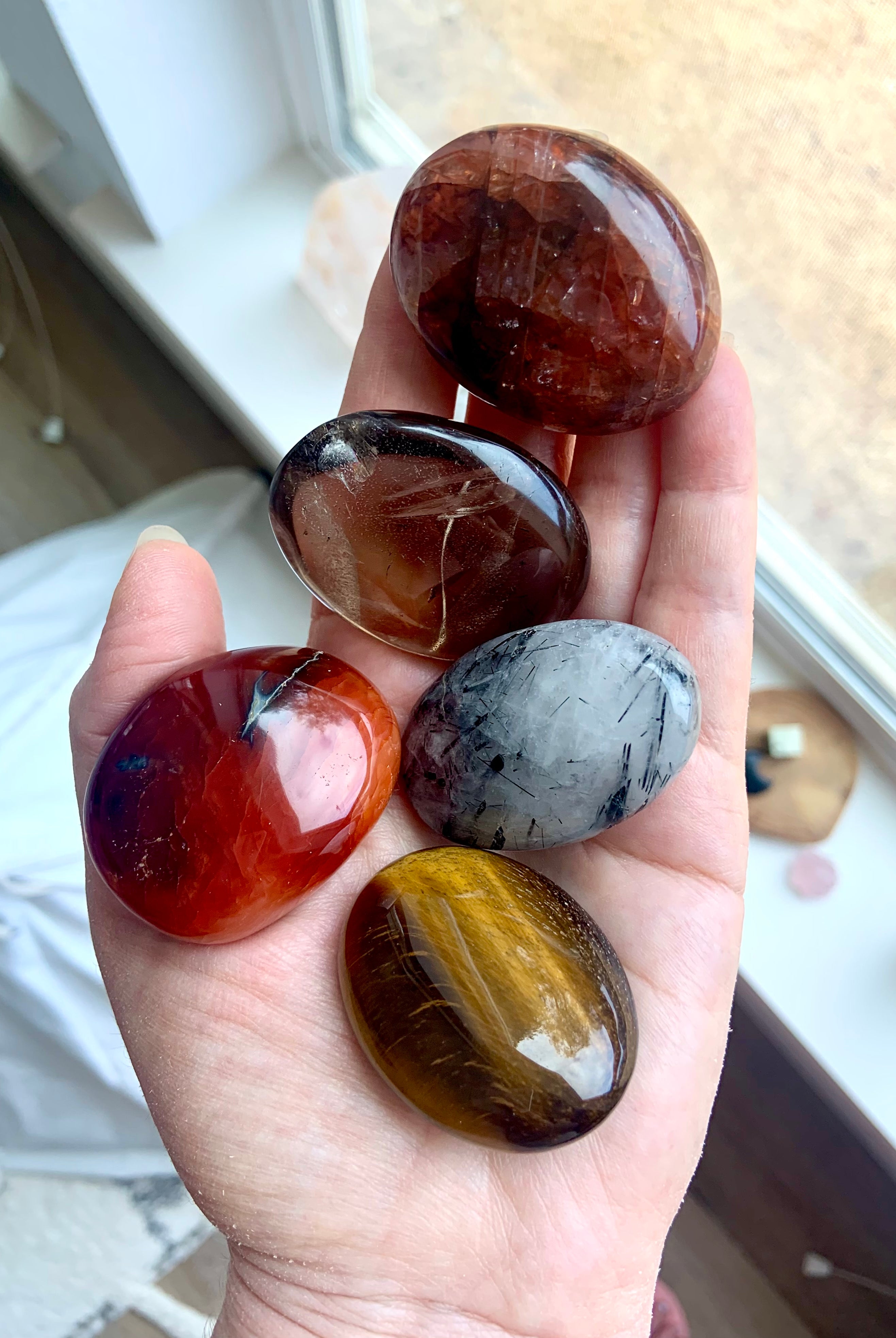 Chakra palm stone set shown on hand — earthy crystals to support grounding, energy flow & lower chakra balance.