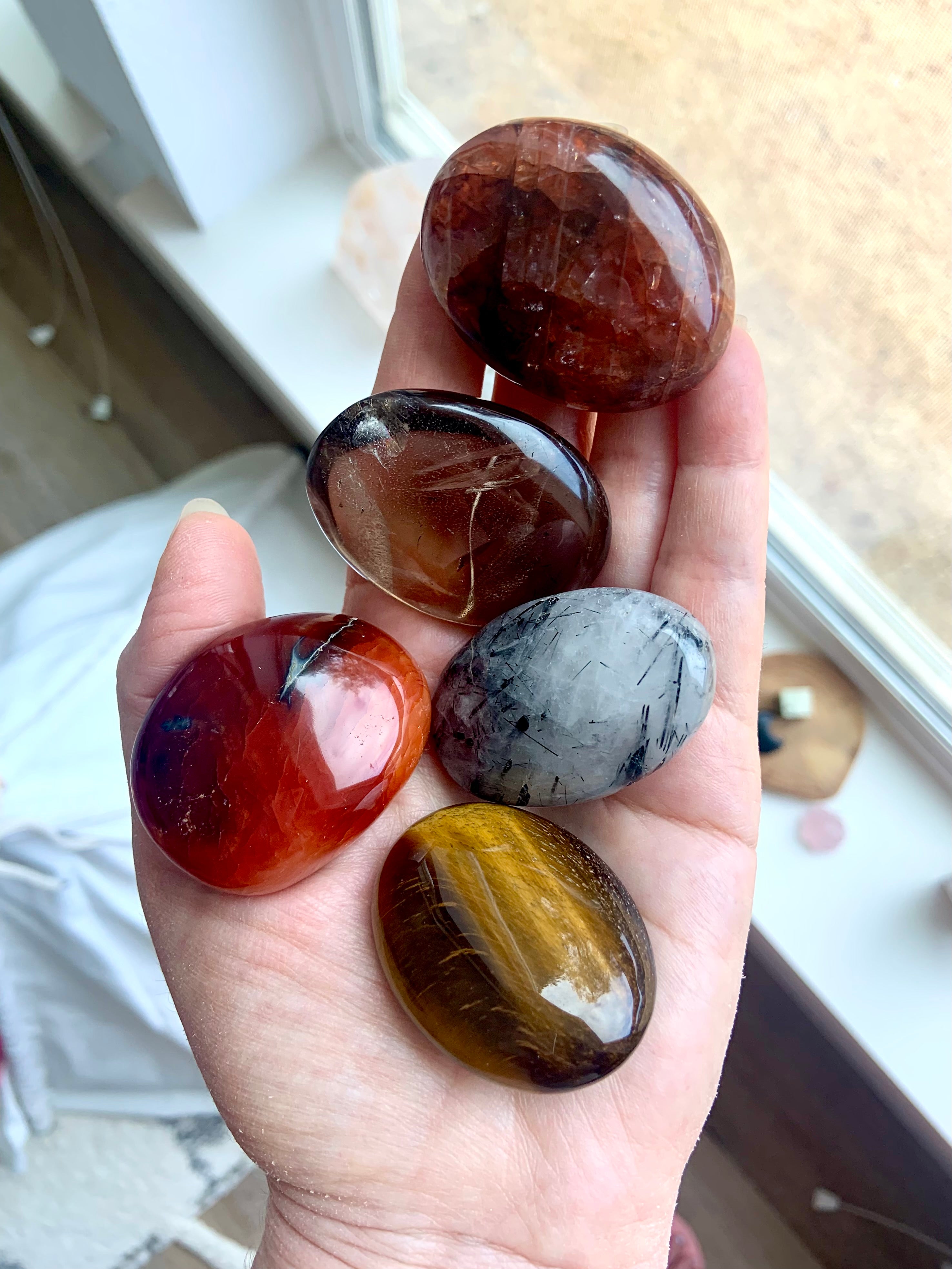 Chakra palm stone set shown on hand — earthy crystals to support grounding, energy flow & lower chakra balance.