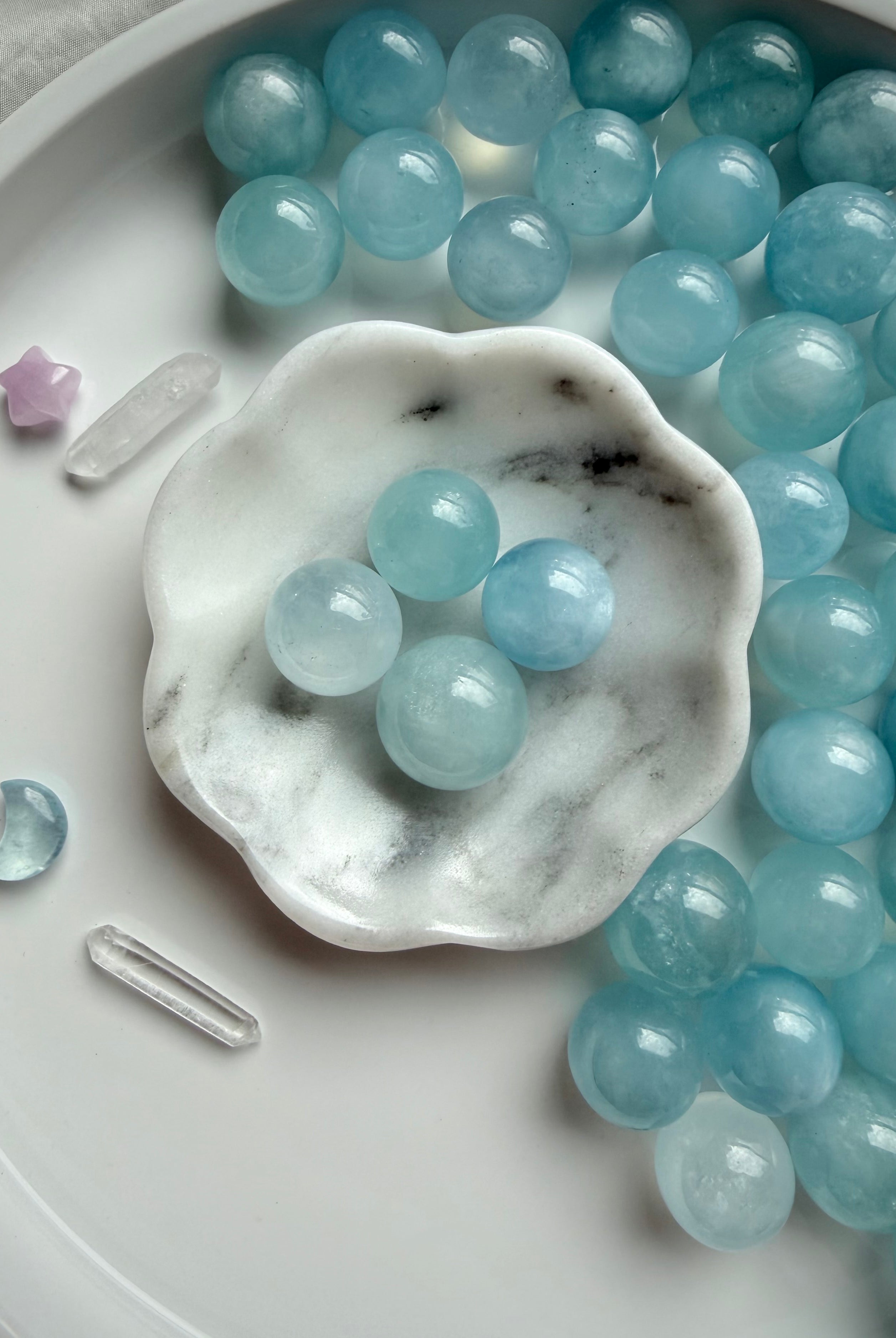 Polished Aquamarine sphere in soft ocean blue – mini March birthstone crystals styled in marble bowl