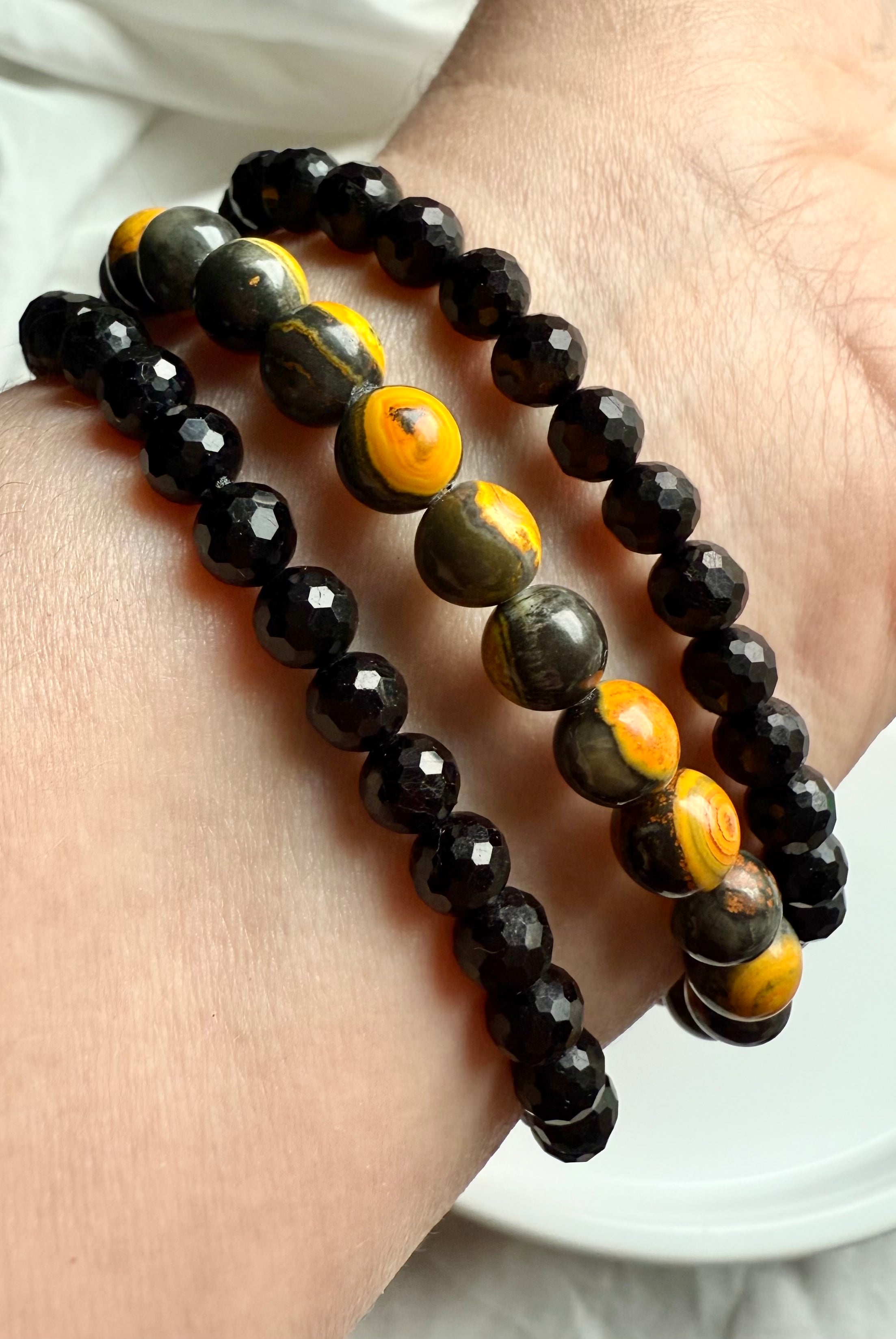 black tourmaline and bumblebee jasper bracelets stacked on wrist, combining bold protection with solar plexus activation