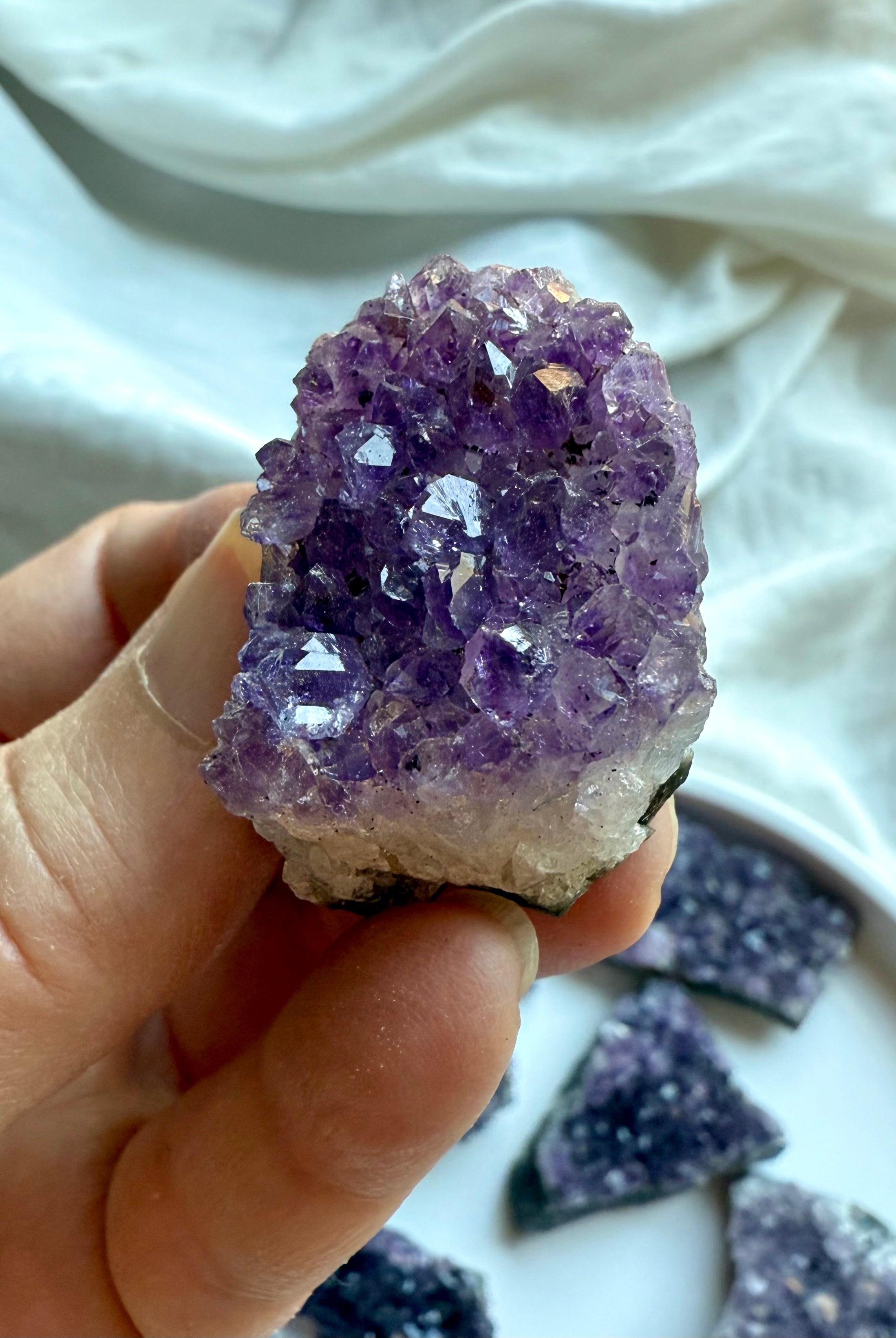 Amethyst cluster with sparkling purple points held in hand + natural chalcedony geode matrix edges