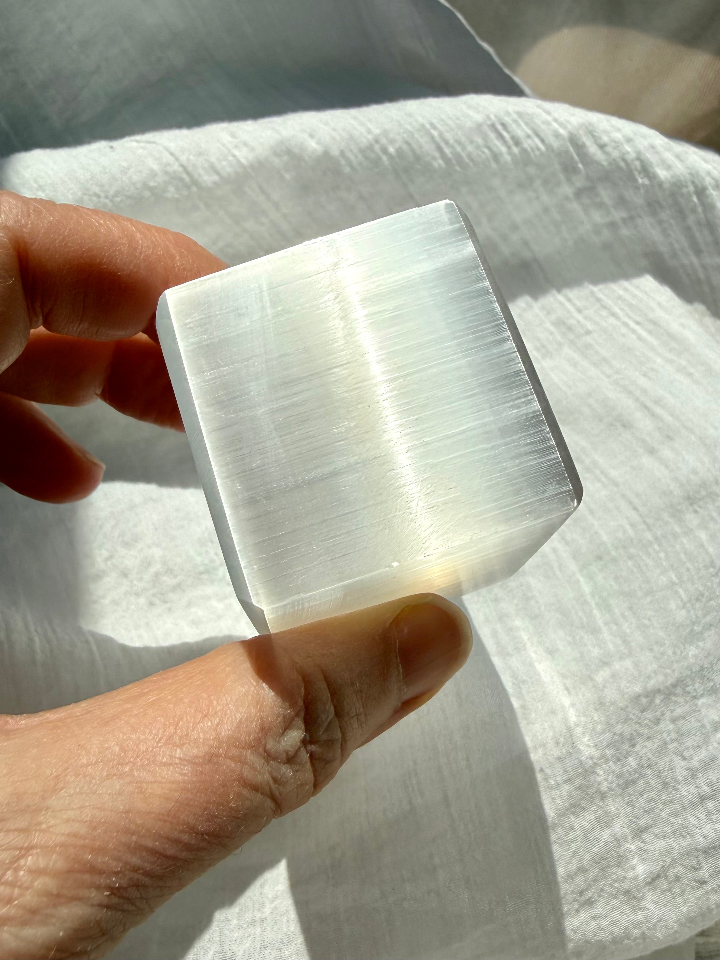 Natural Selenite cube held in hand with silky fibrous layers for crystal cleansing and energy clearing
