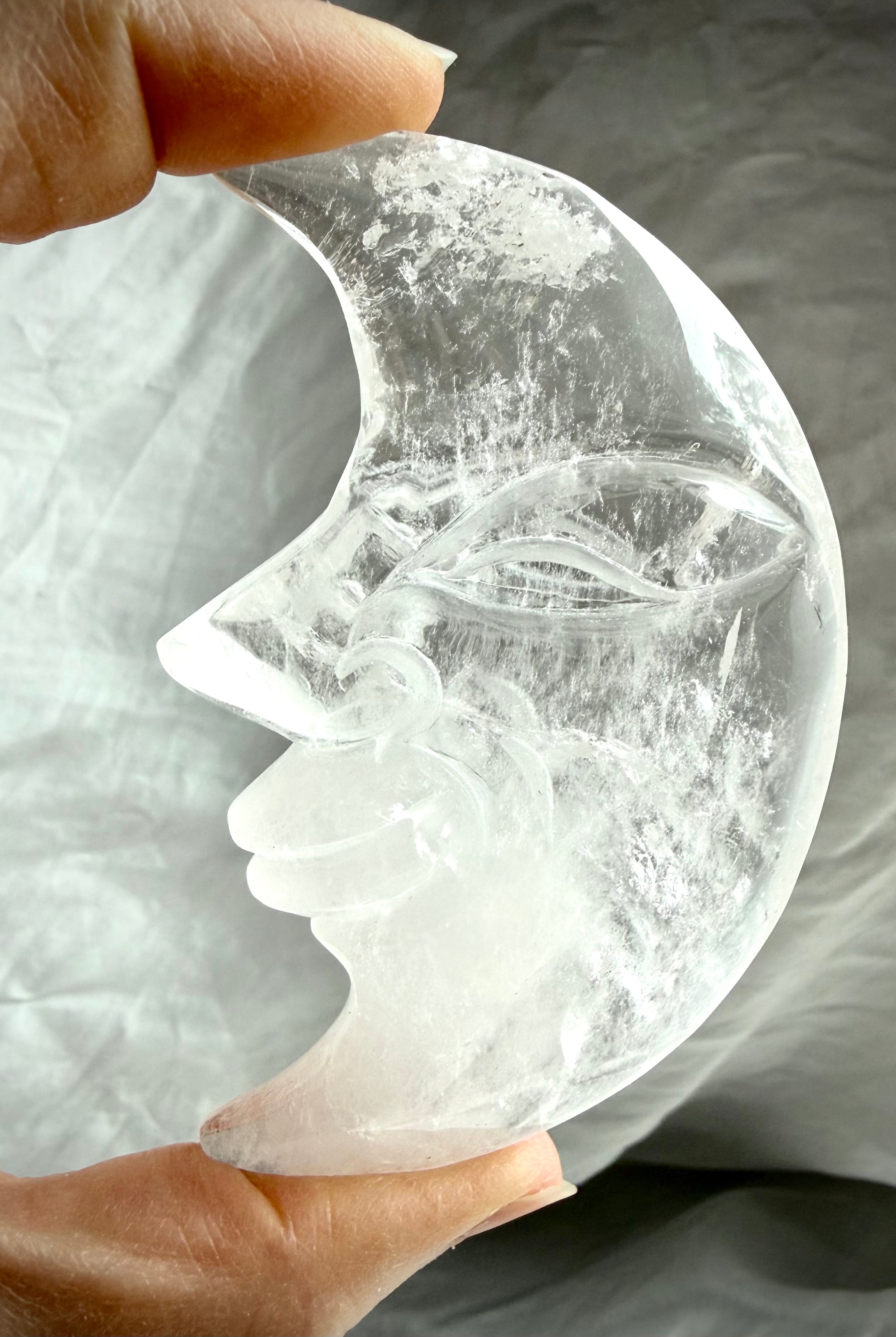 Close-up of Clear Quartz Moon Face carving highlighting detailed facial features and luminous transparent crystal