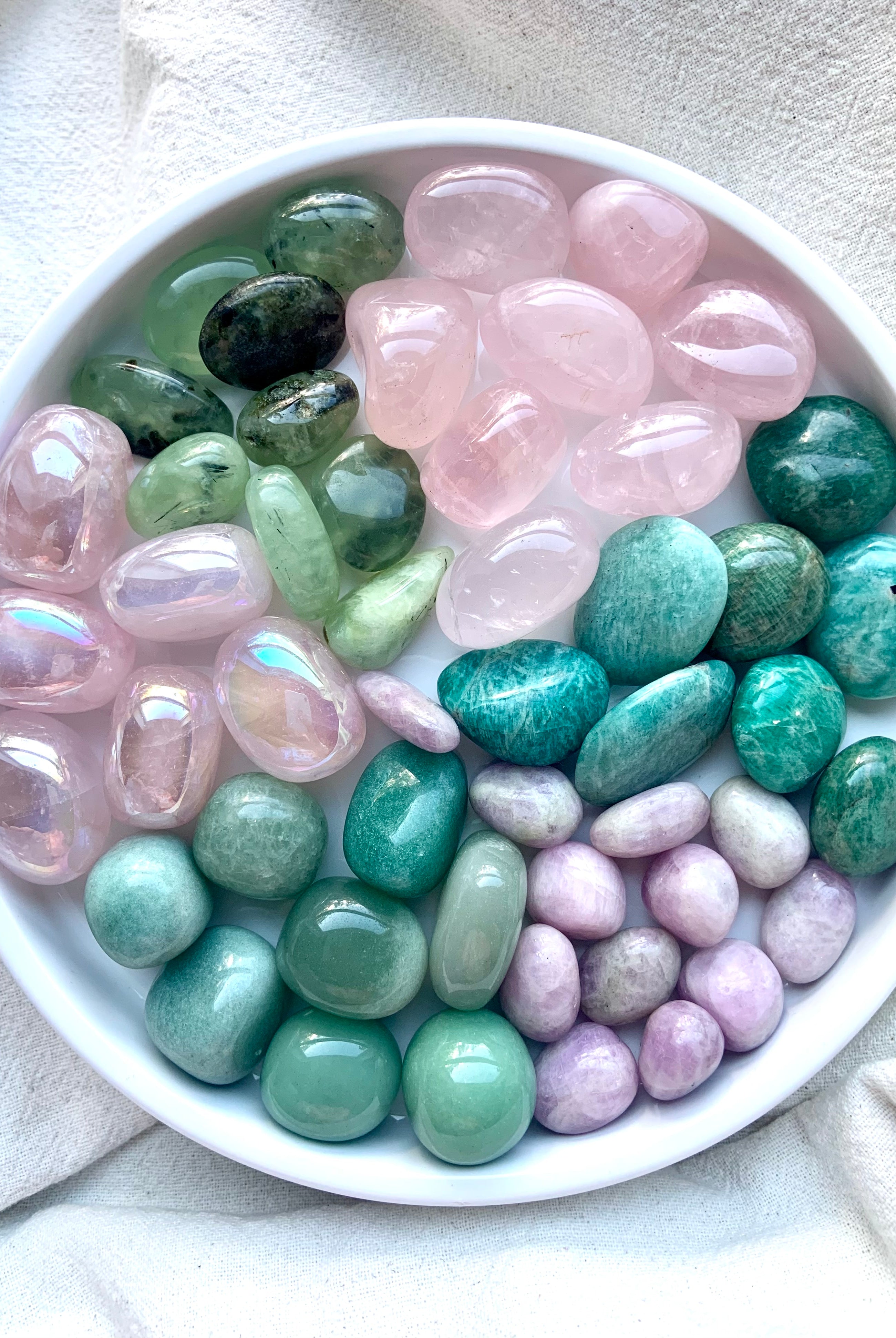 Overhead image of Heart Chakra stones arranged on a white plate — a full set of pink and green crystals for chakra alignment and heart-centered energy healing.