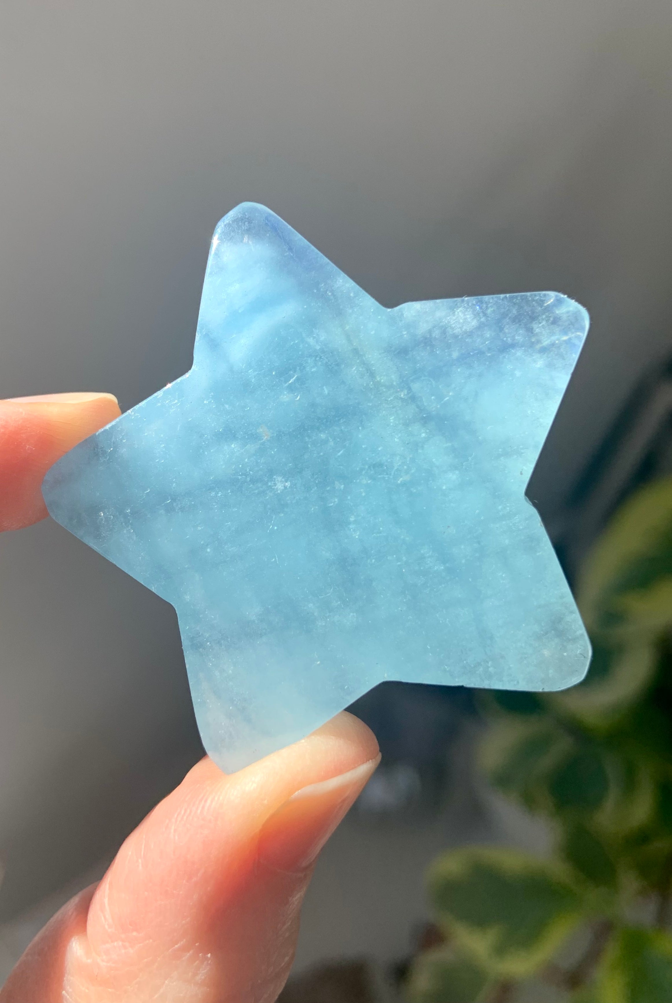 Larger Aquamarine star held to the light to show translucent blue shimmer of the natural gemstone