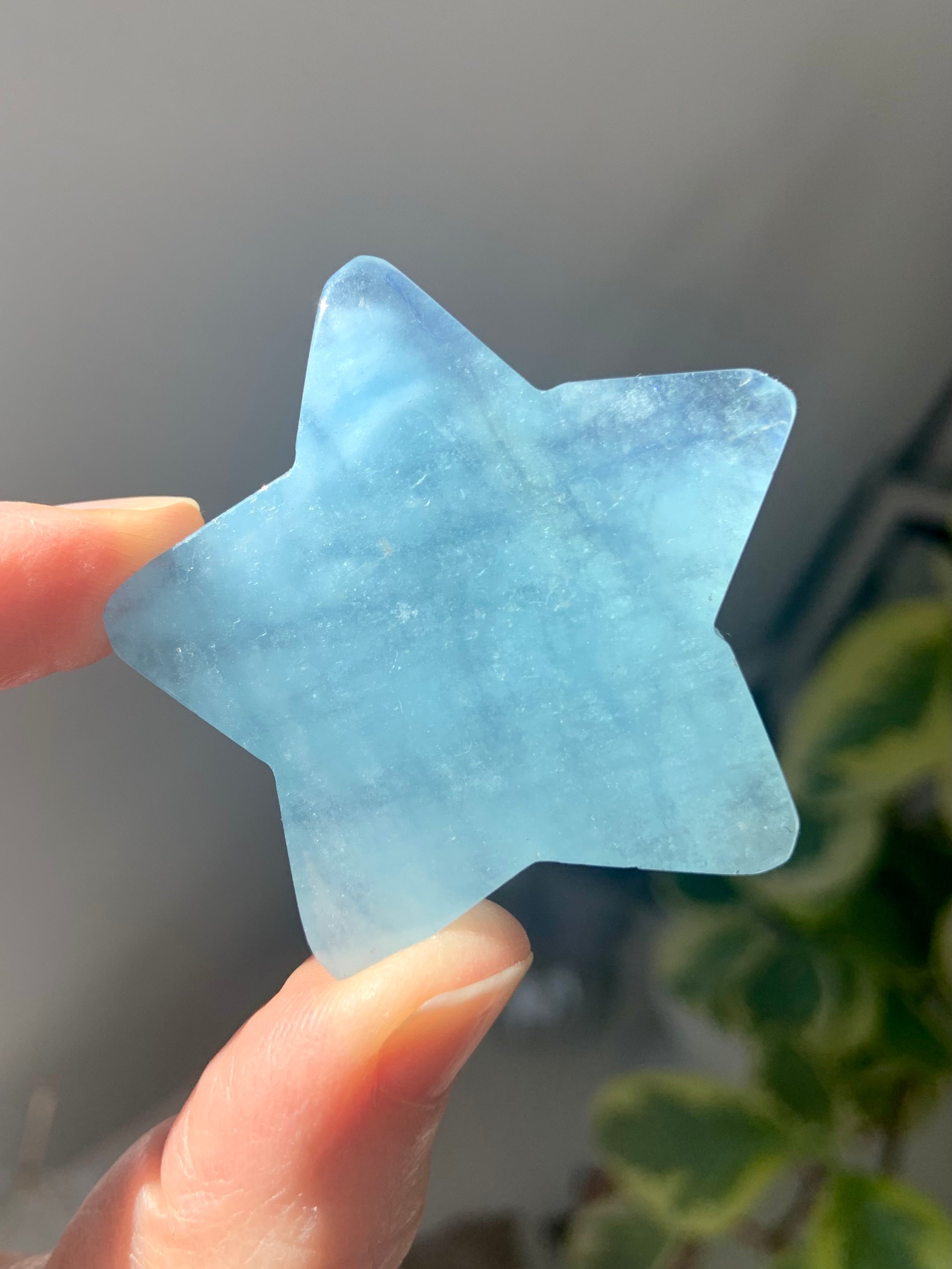 Larger Aquamarine star held to the light to show translucent blue shimmer of the natural gemstone