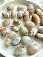 Two sizes of high quality Flower Agate tumbled stones with beautiful pastel colors on a white plate