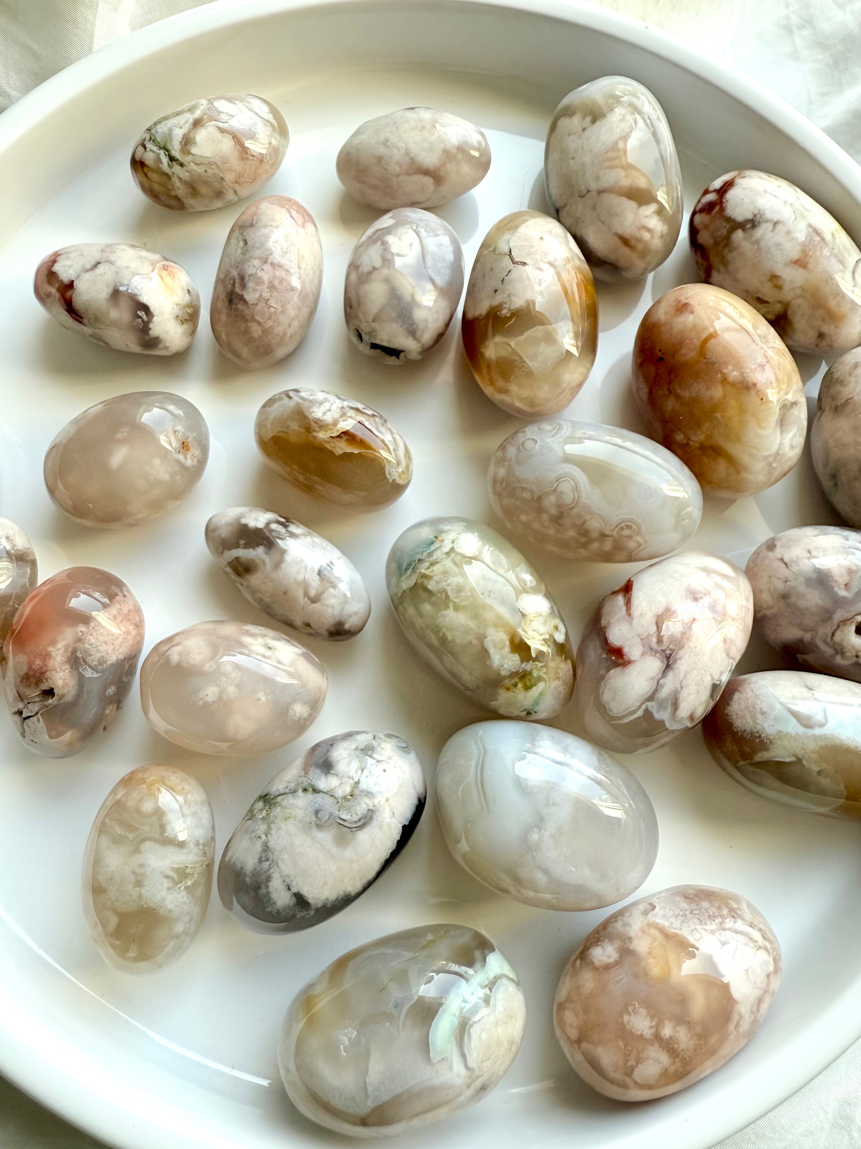 Two sizes of high quality Flower Agate tumbled stones with beautiful pastel colors on a white plate