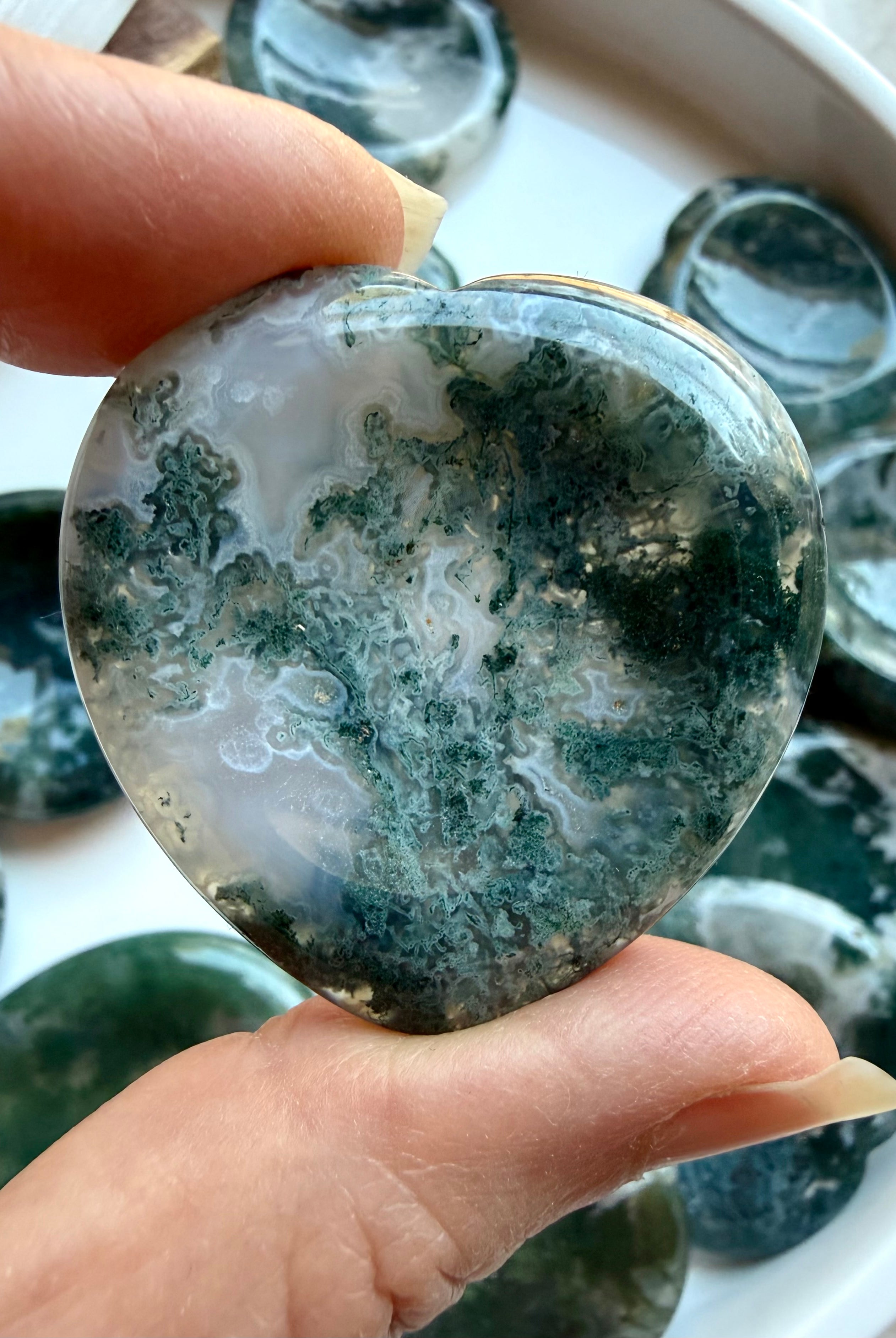 Moss Agate heart worry stone held in hand with rich moss inclusions and natural translucent quartz