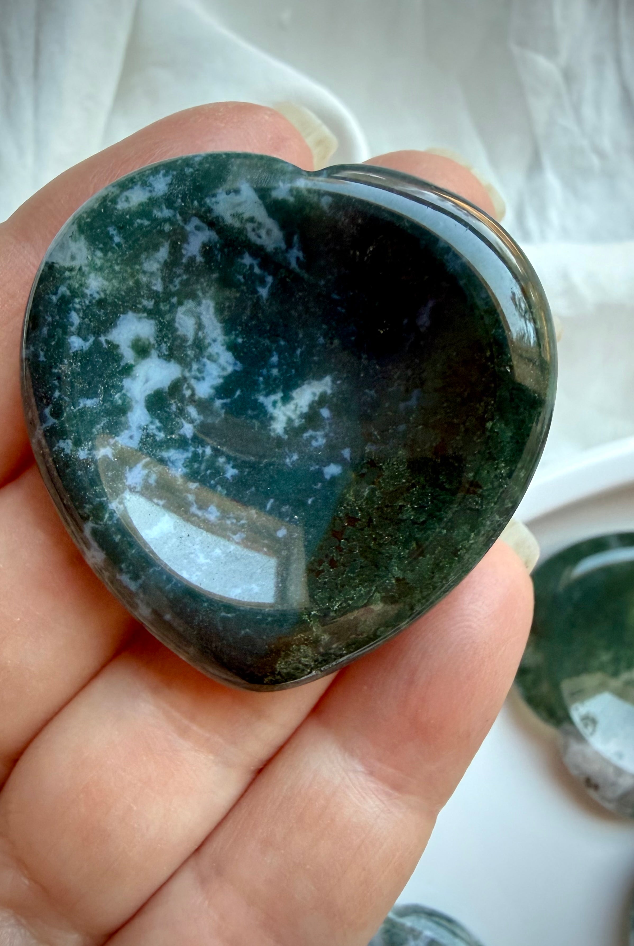 Moss Agate heart worry stone held in hand with dense forest green dendritic inclusions