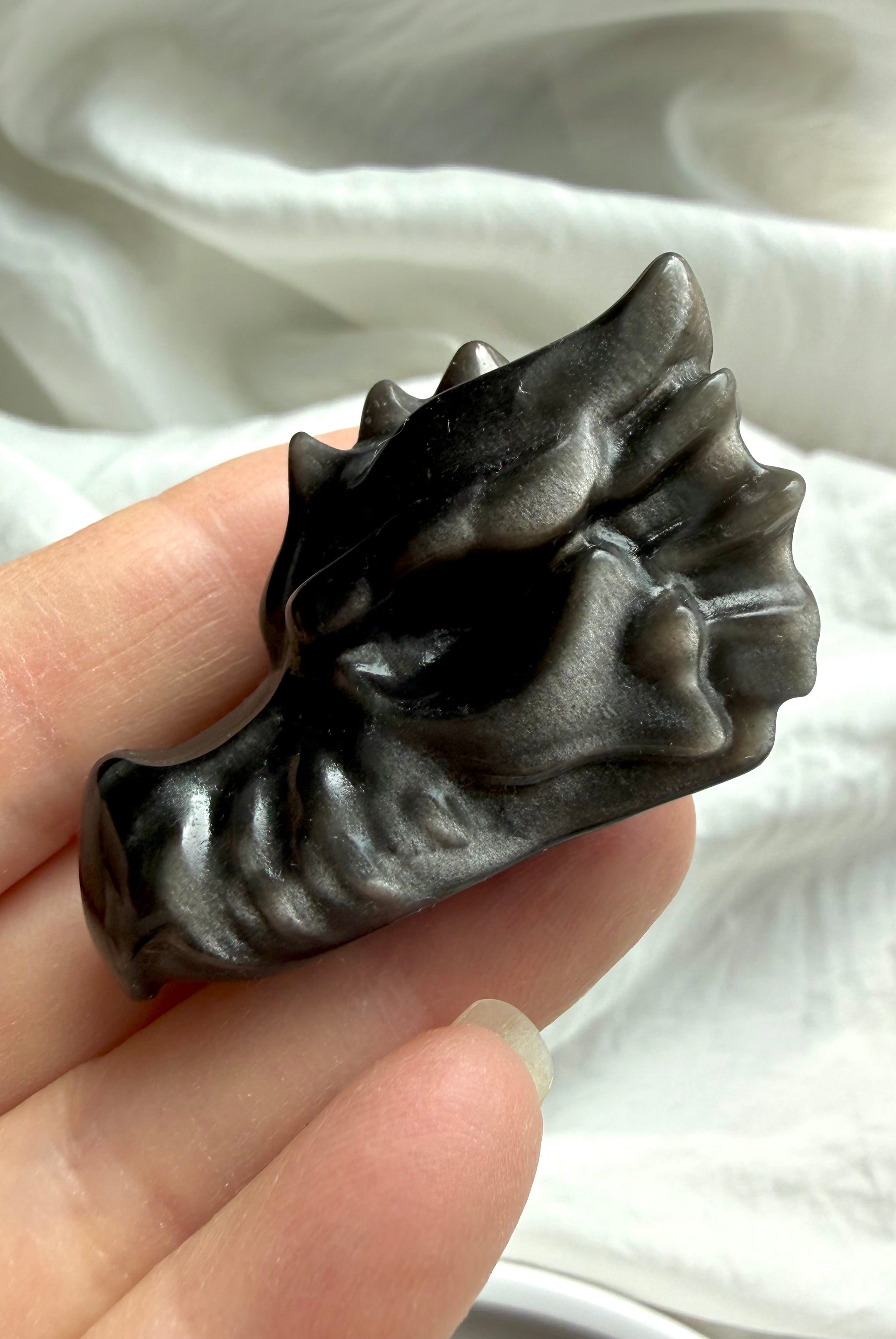 silver sheen obsidian dragon carving in hand with visible sheen effect, protective stone for transformation clarity and balance