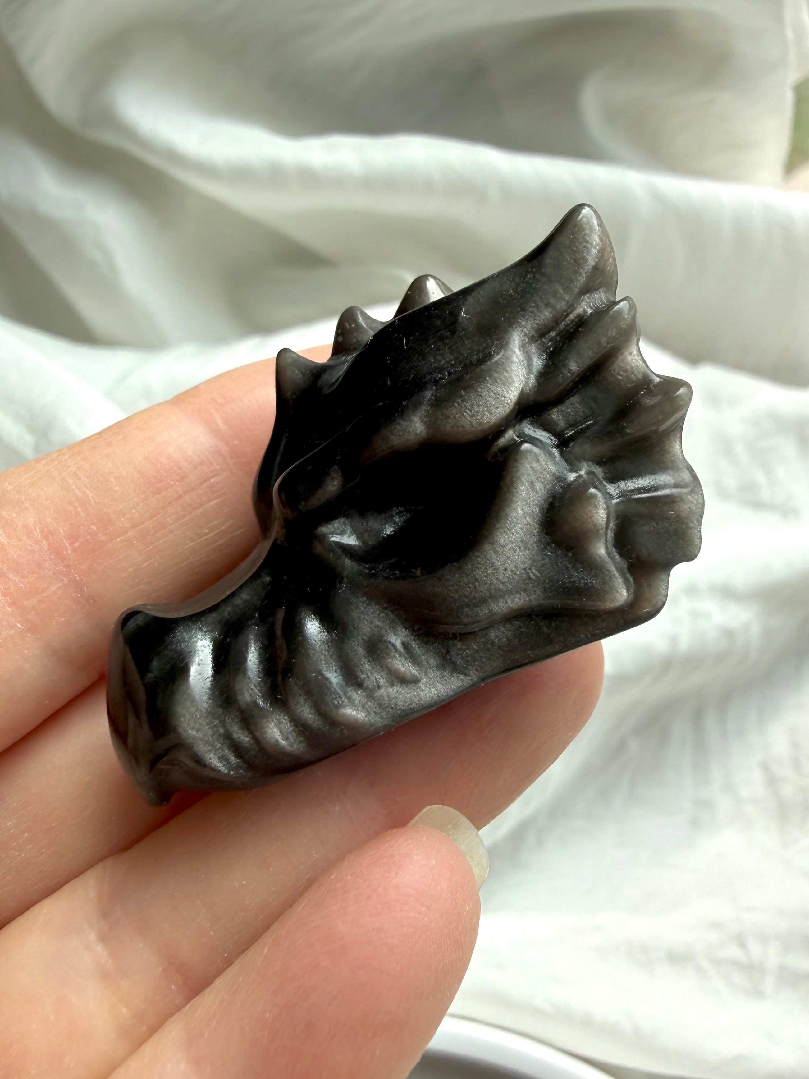 silver sheen obsidian dragon carving in hand with visible sheen effect, protective stone for transformation clarity and balance