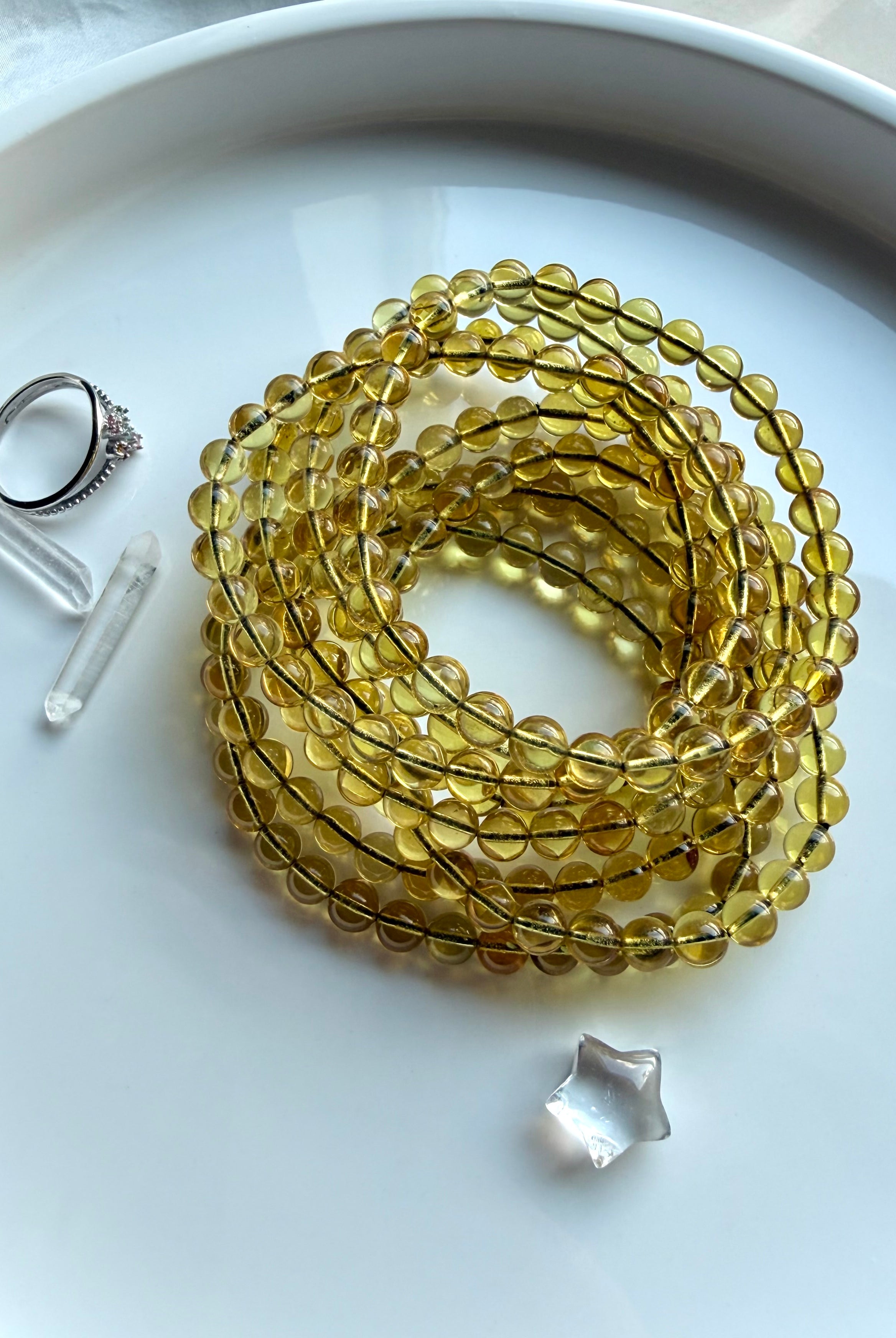 Indonesian blue amber bead bracelets coiled on dish – UV reactive amber crystal jewelry