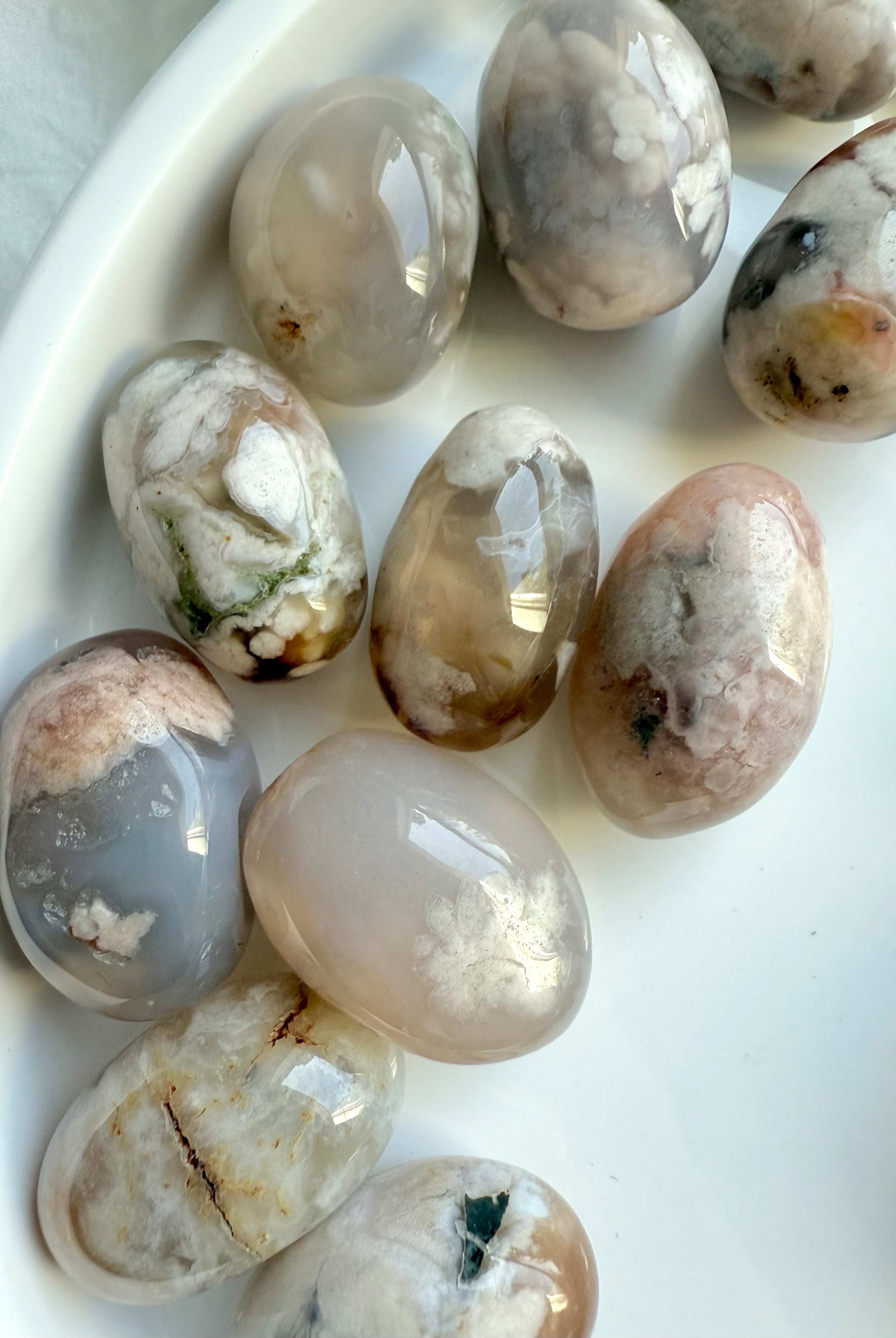 Close up of high quality Flower Agate tumbled stones with beautiful pastel colors on a white plate