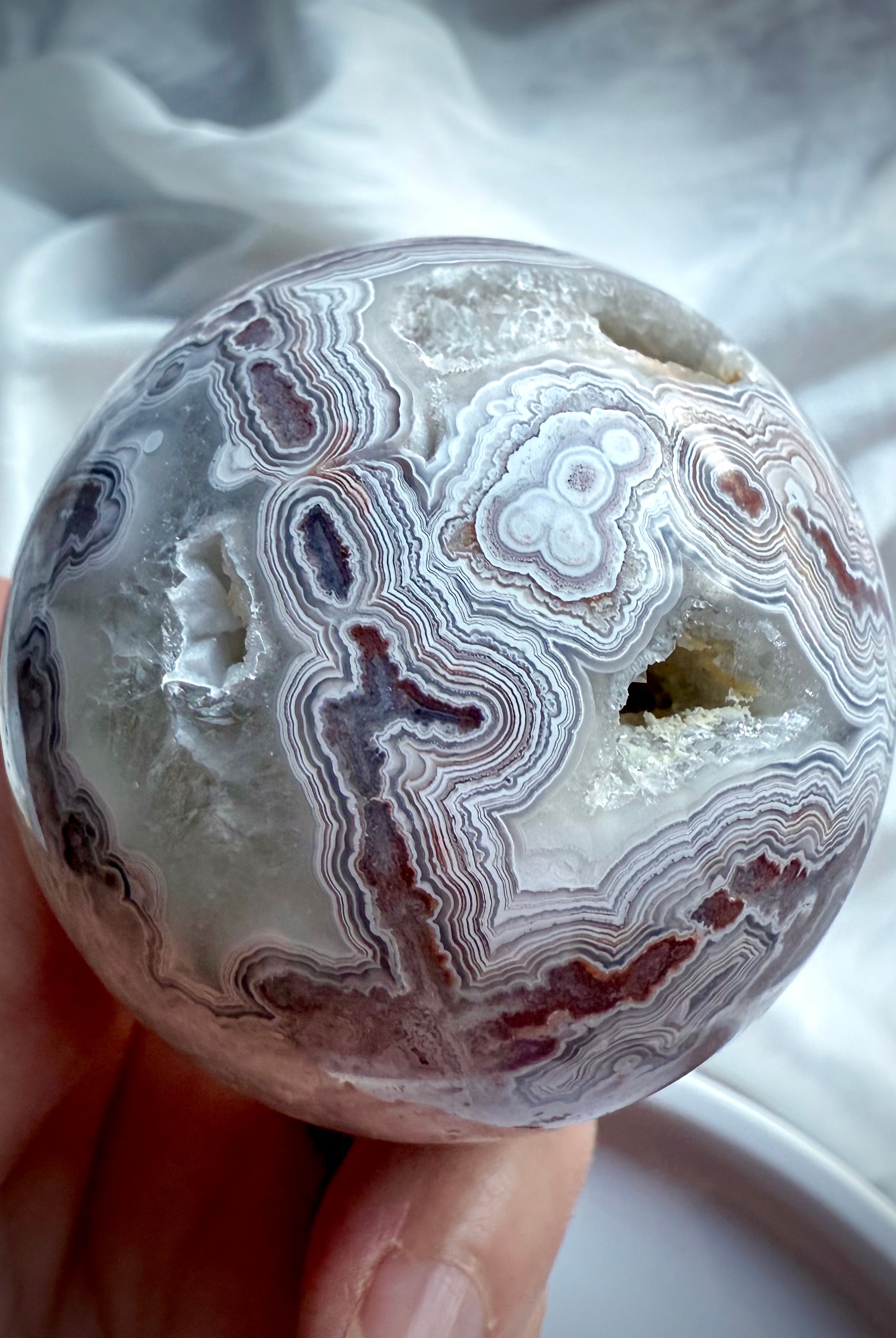 Joyful Crazy Lace Agate sphere showing deep red lace patterns, open geode cavity, and intricate natural banding