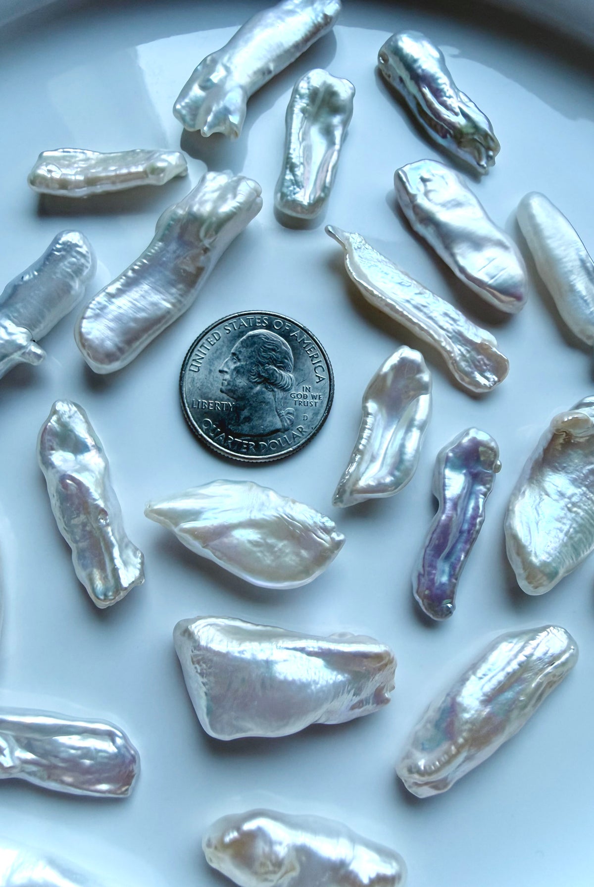 Freshwater Baroque Stick Pearls with luminous pearlescent luster and naturally varied elongated shapes, shown with a US quarter for scale