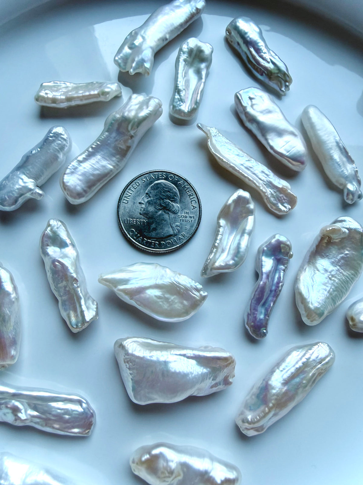 Freshwater Baroque Stick Pearls with luminous pearlescent luster and naturally varied elongated shapes, shown with a US quarter for scale