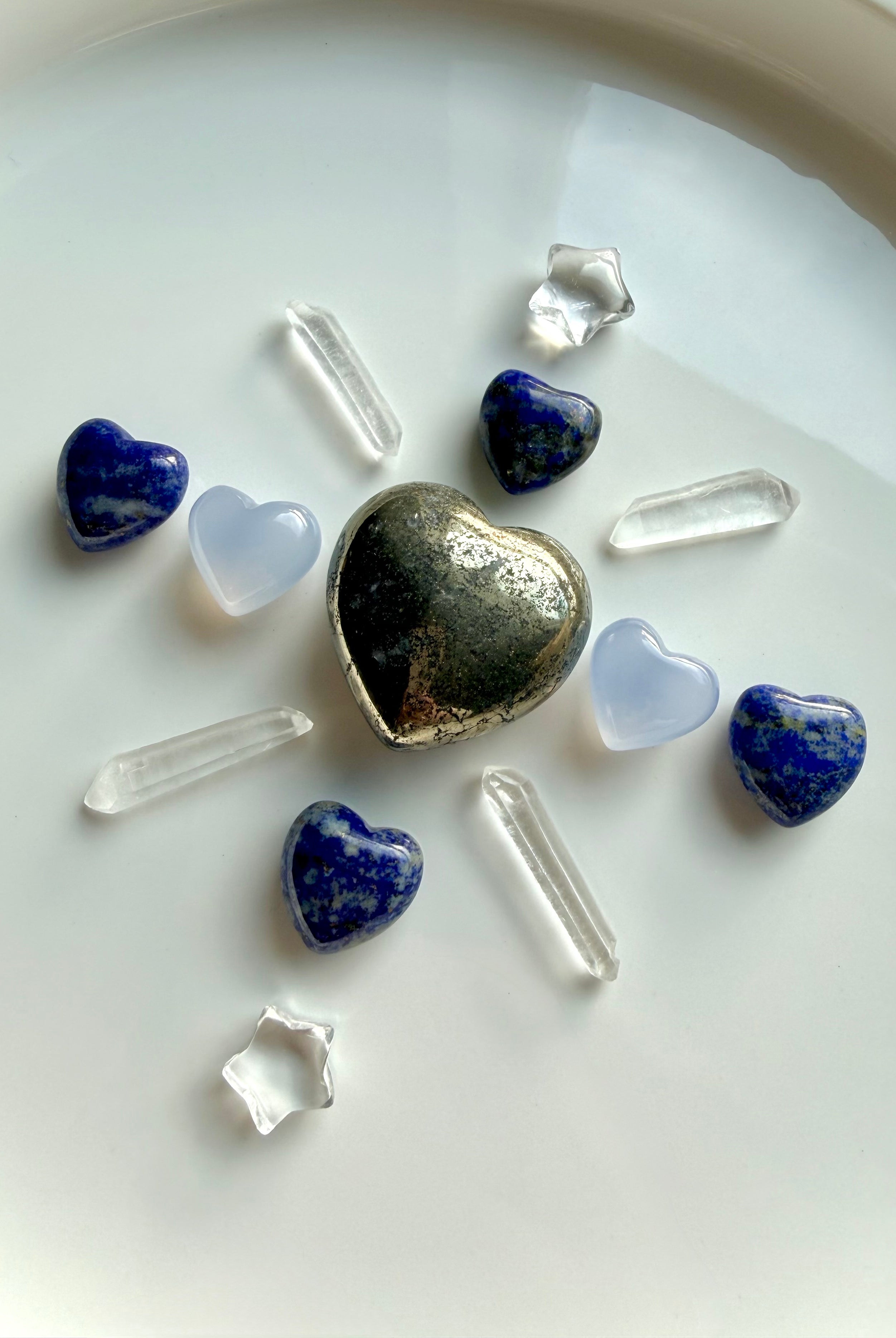Crystal grid featuring pyrite heart centerpiece with blue chalcedony hearts, lapis lazuli hearts, clear quartz points, and star carvings for clarity, communication, and heart-centered intention