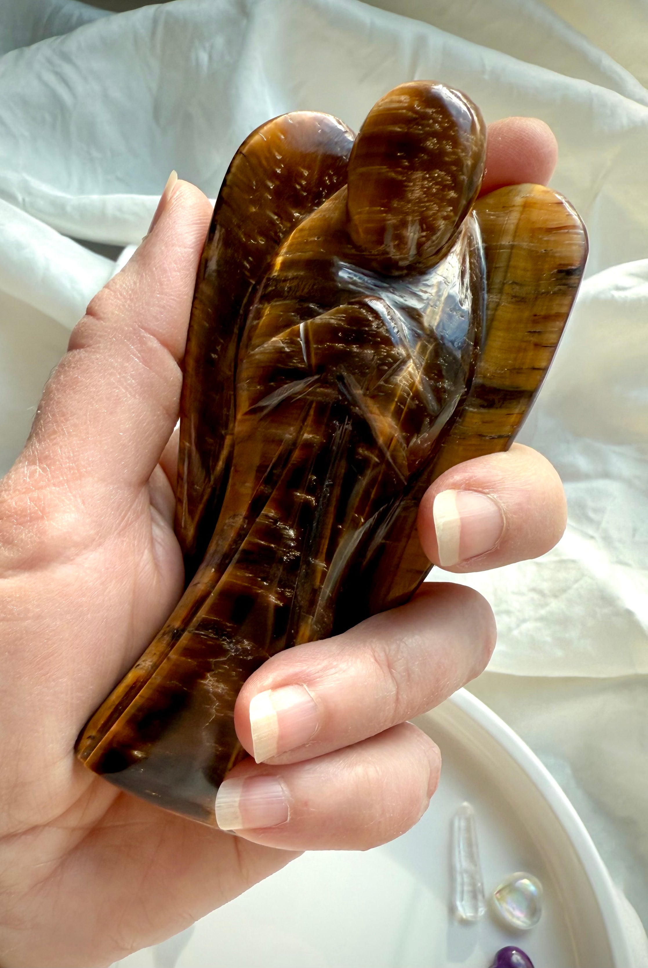 Golden Tiger’s Eye angel carving held in hand to show size and polished surface detail