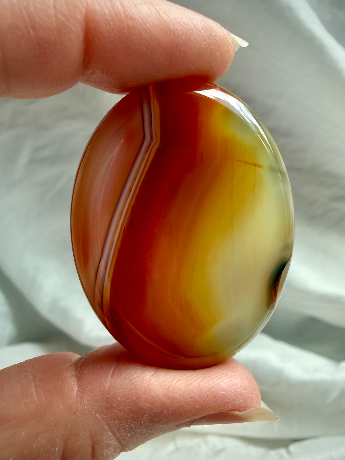 Translucent Carnelian Agate worry stone with golden yellow and red banding, polished crystal for creativity and vitality