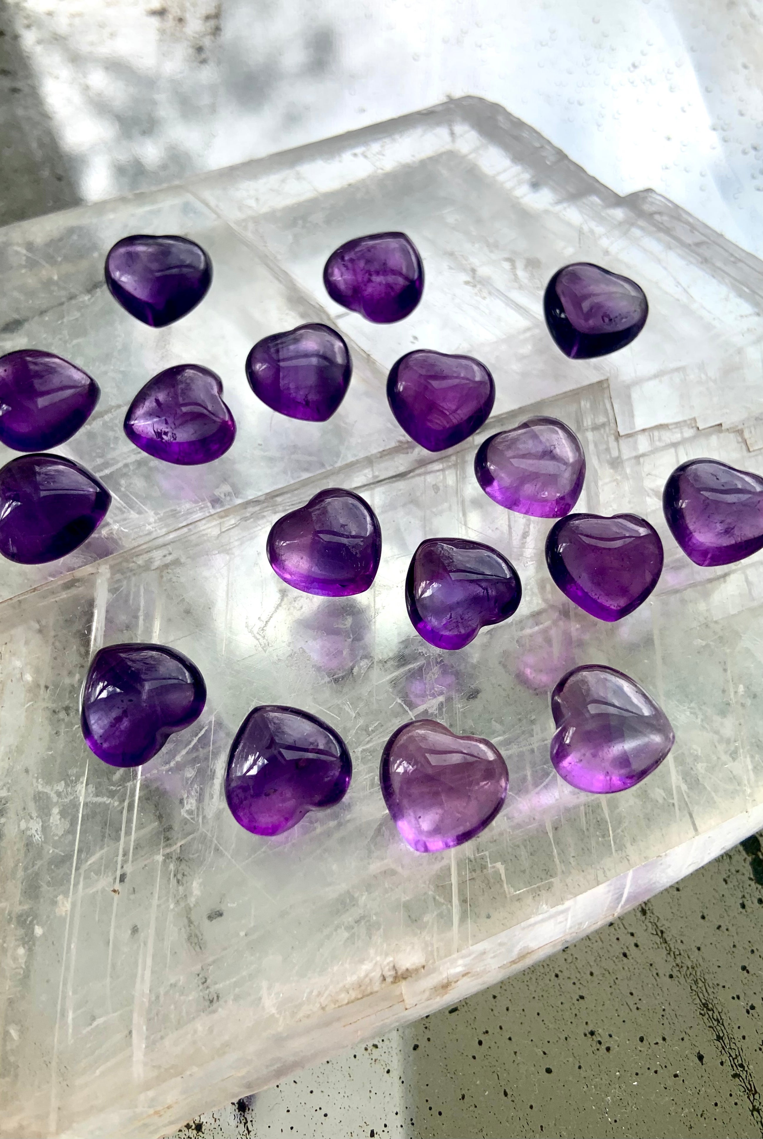 Angled view of mini Amethyst hearts on a selenite slab — heart-shaped crystals for clarity and connection