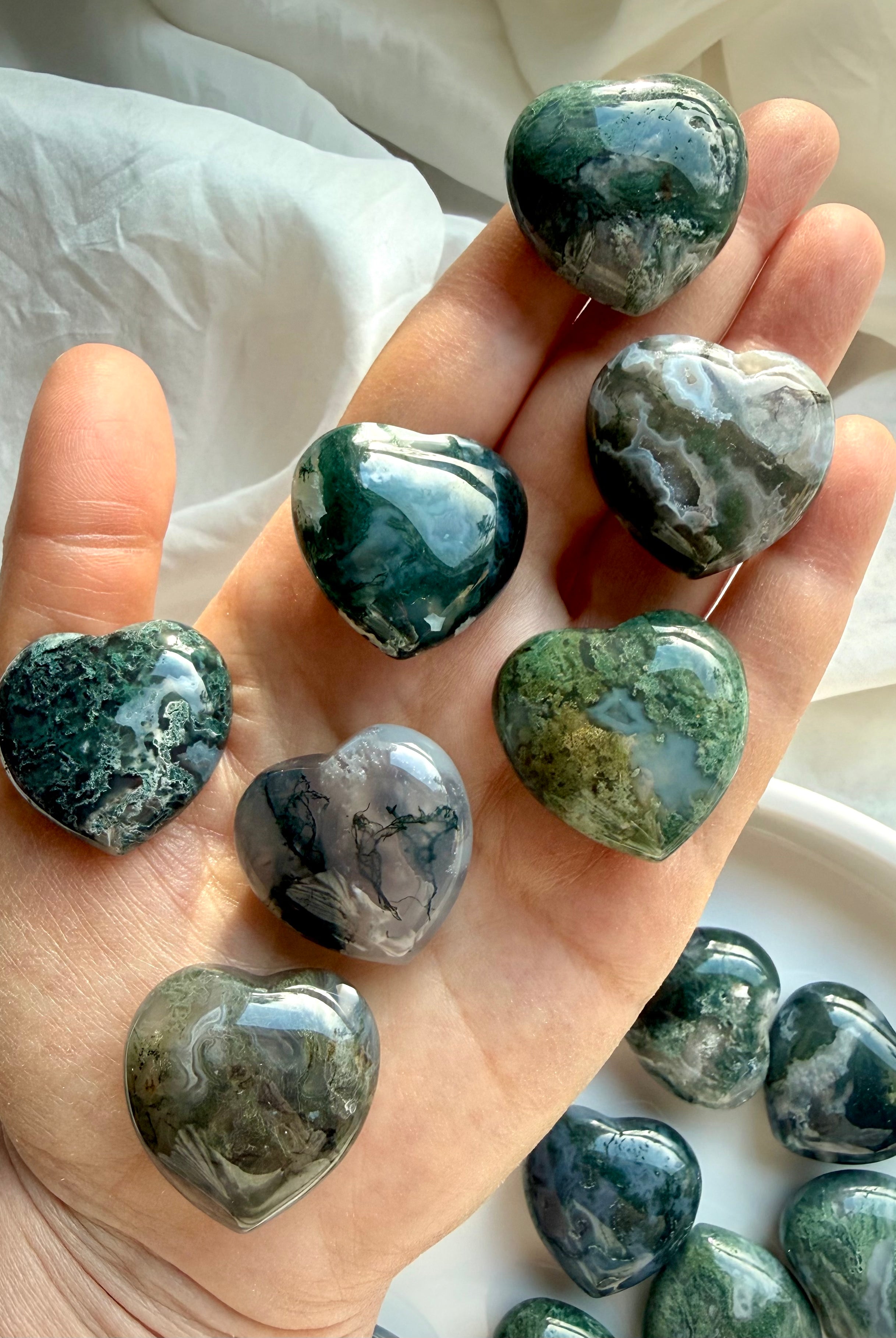 Moss Agate crystal hearts held in hand, showing size, polish, and natural moss inclusions