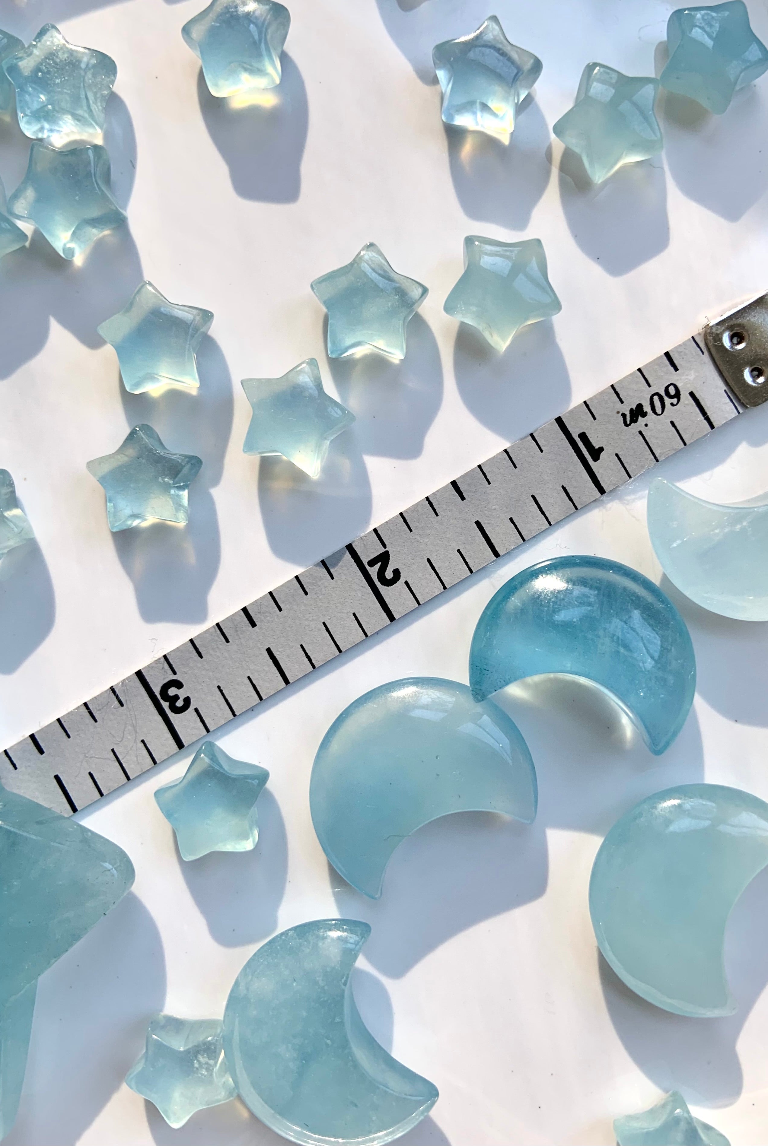 Luminous blue aquamarine moons and stars with measuring tape for size reference