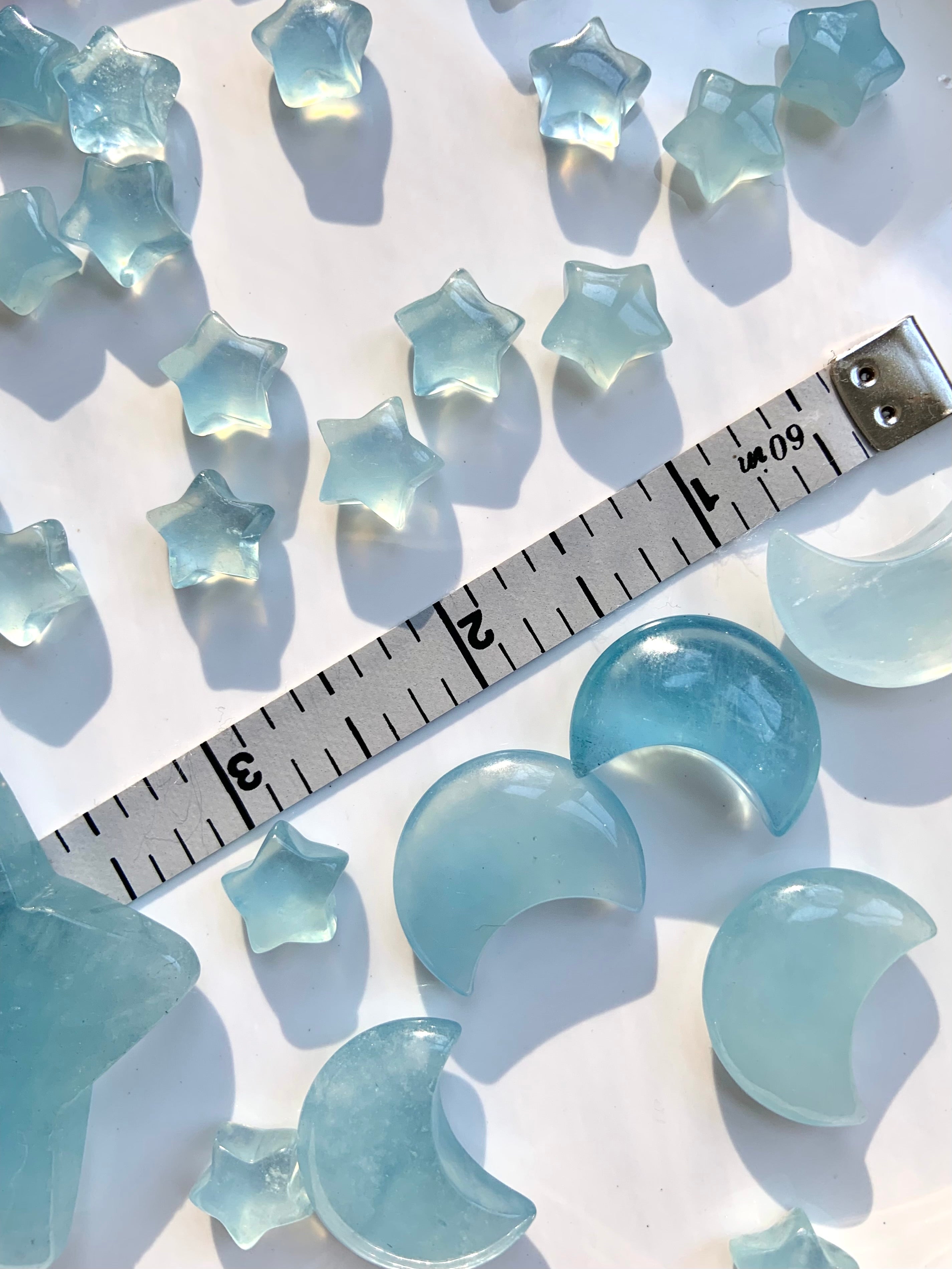 Luminous blue aquamarine moons and stars with measuring tape for size reference