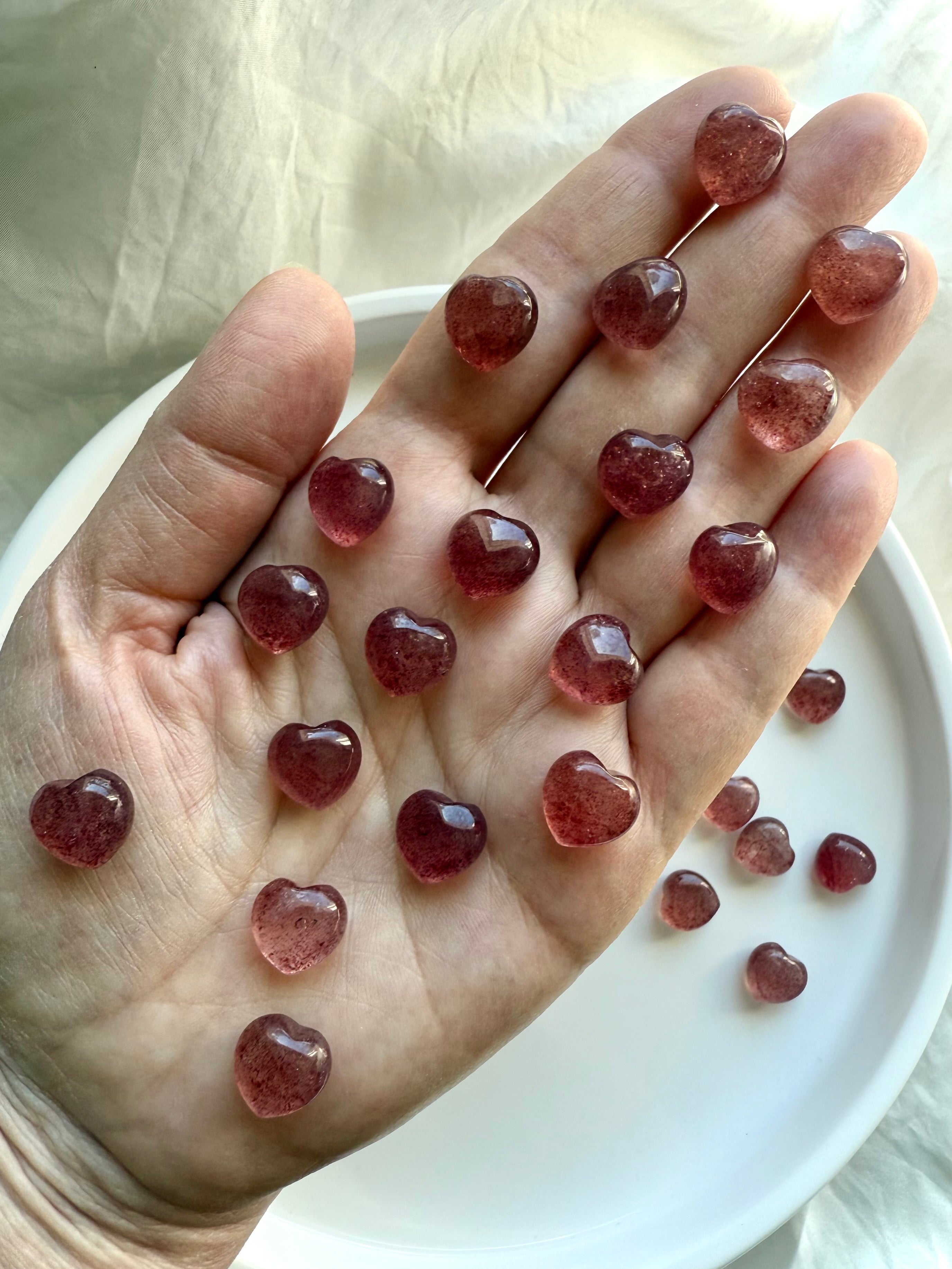Array of tanzberry quartz mini hearts on a hand — heart chakra crystals for emotional balance, self-love, and joy.