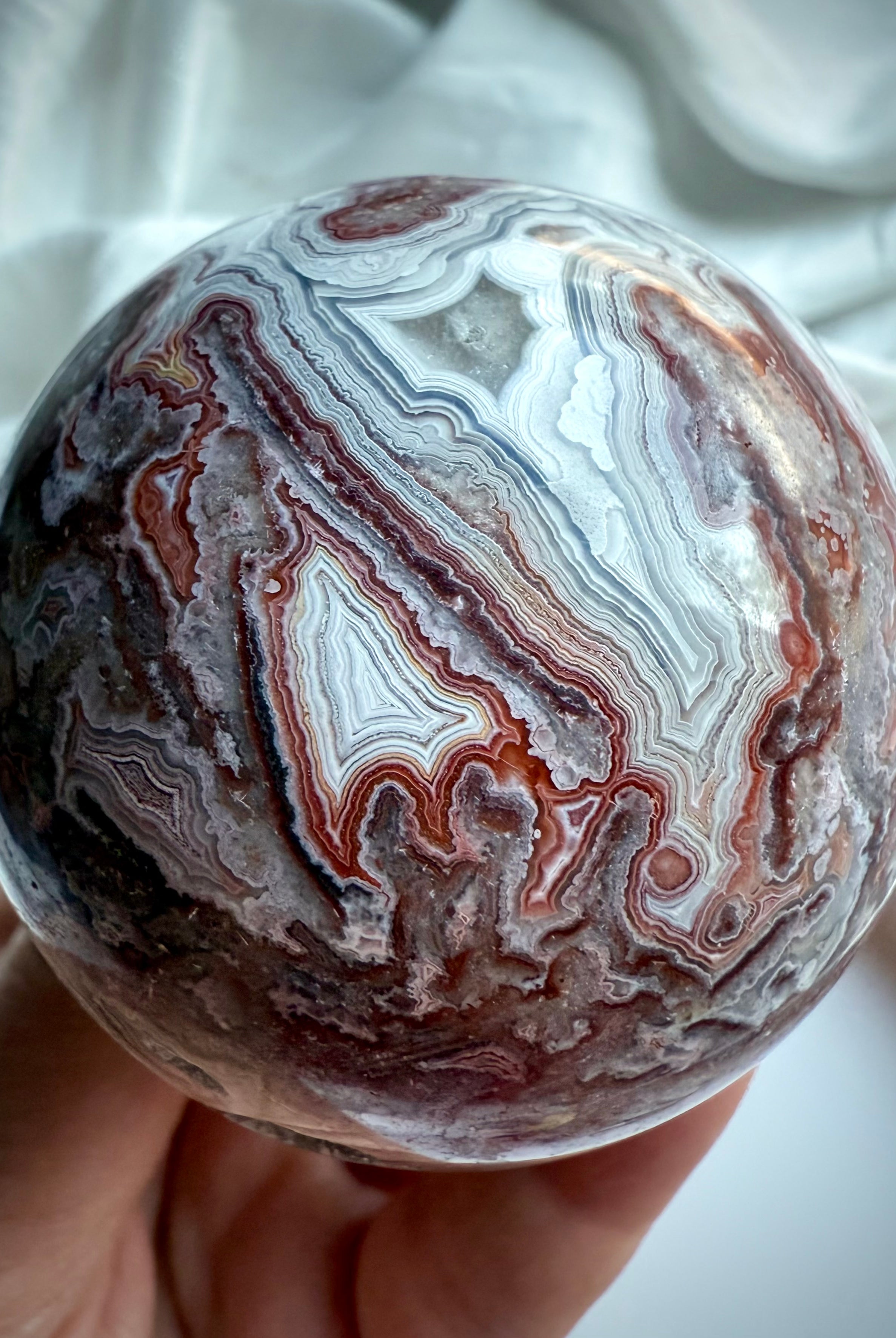 Crystal sphere showcasing lace-like Crazy Lace Agate patterns with deep grounding colors and earthy textures
