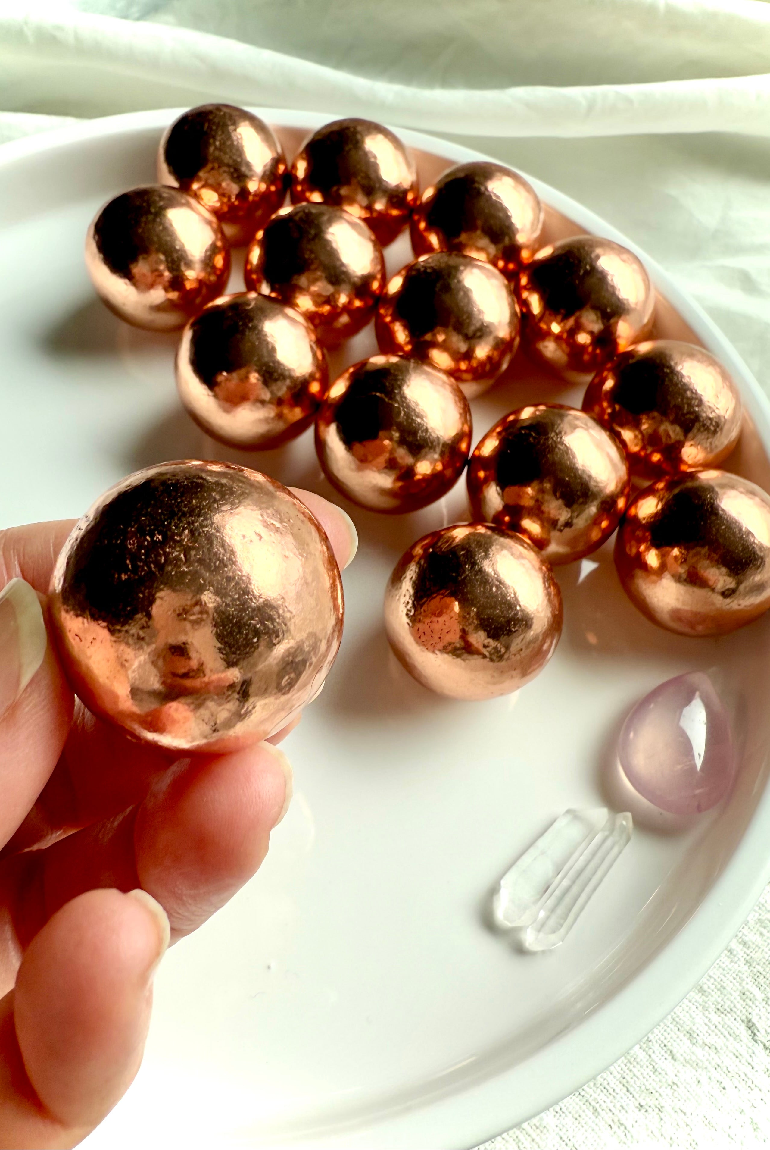 Michigan copper spheres shown in my fingertips for scale with a plate of mini copper balls