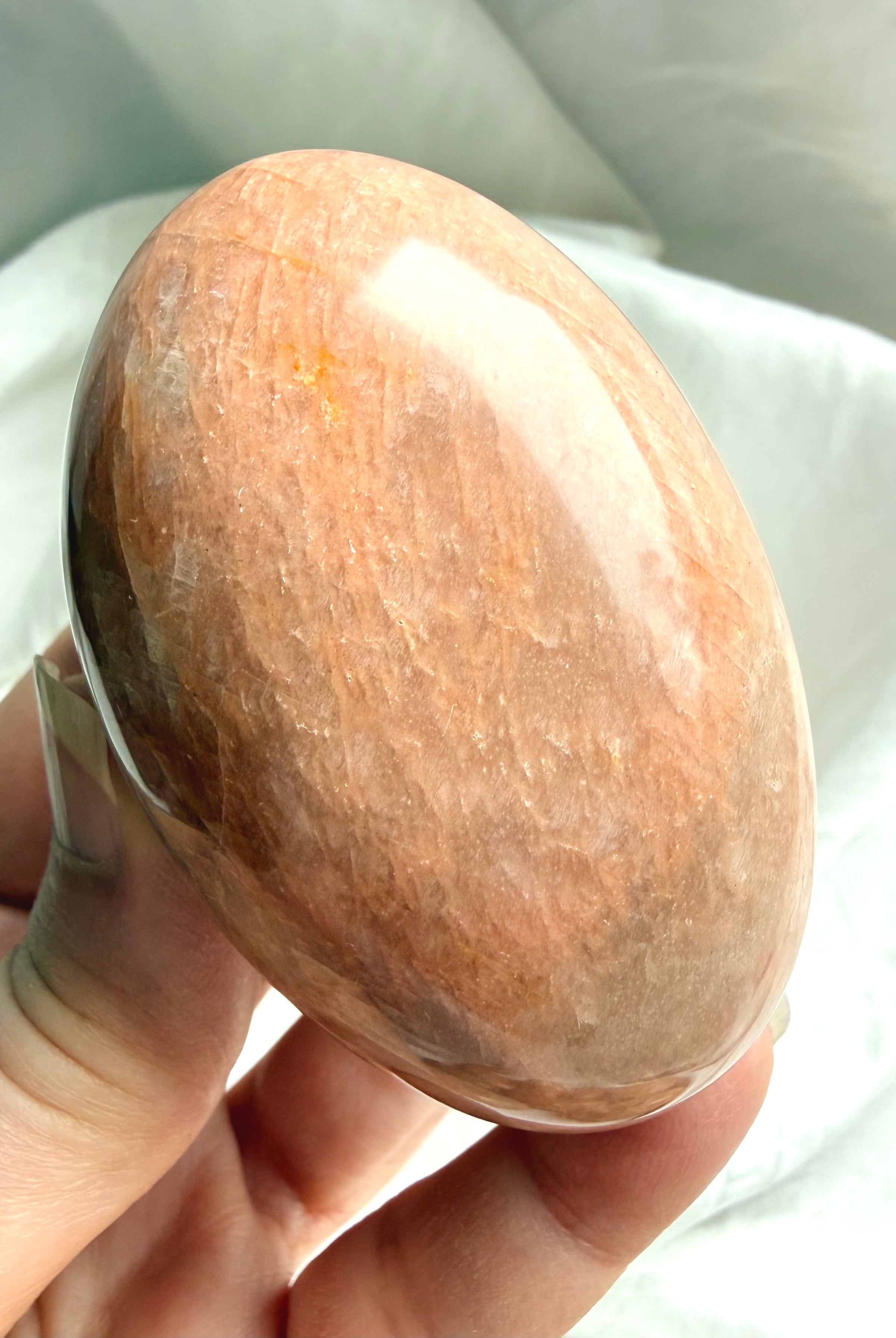 Smooth polished Peach Moonstone palm stone with soft peach and beige natural banding