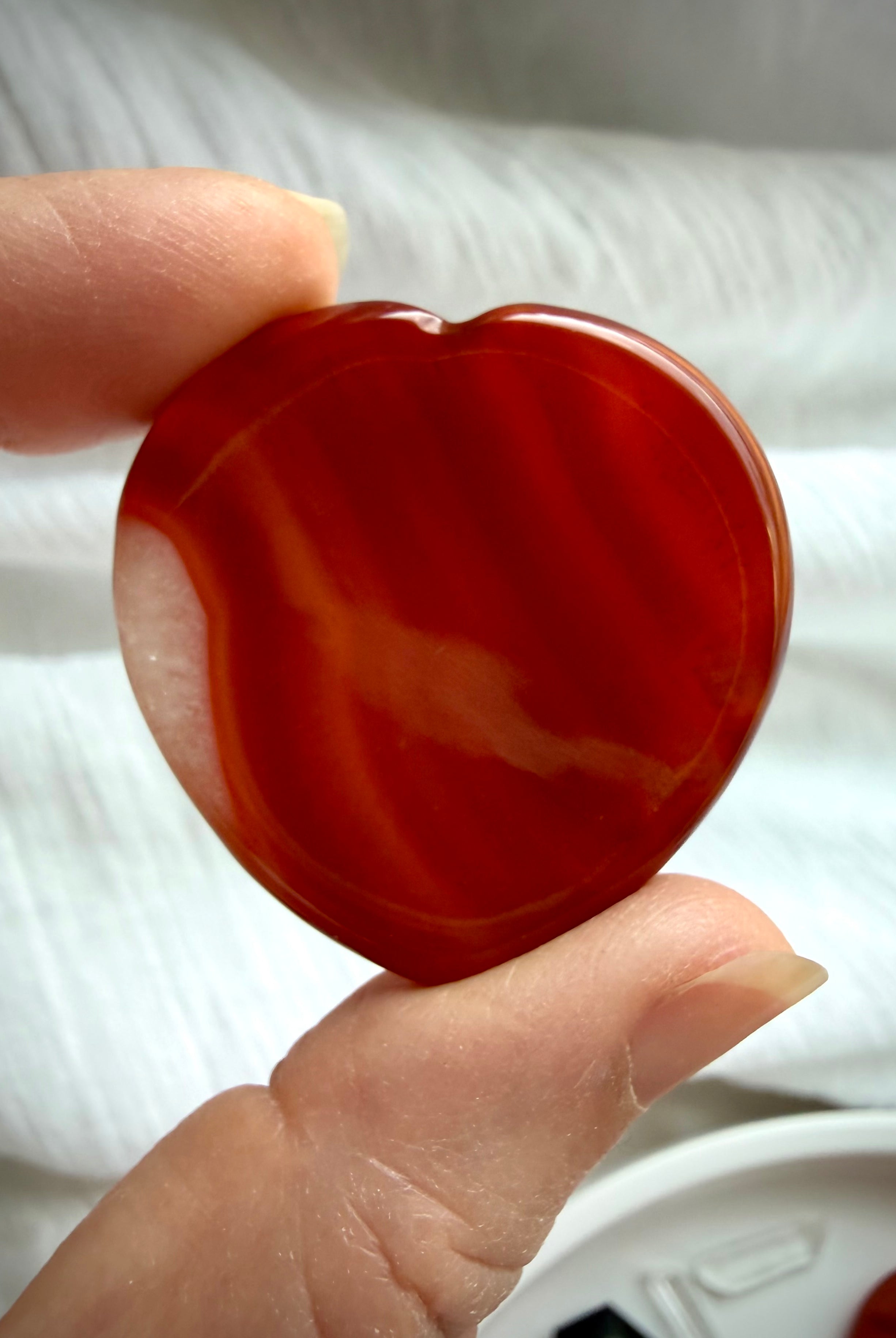 Polished Carnelian heart worry stone with bold red-orange agate banding for creativity, motivation and confidence