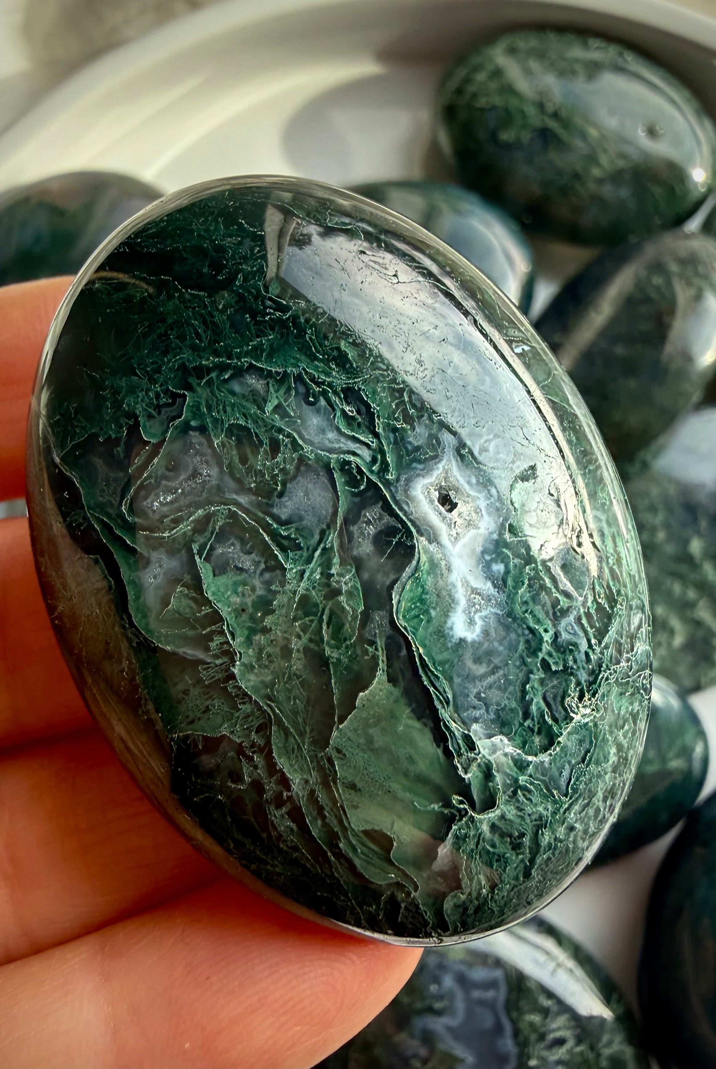Moss agate palm stone held in hand, polished grounding crystal with green moss inclusions for calm and stability