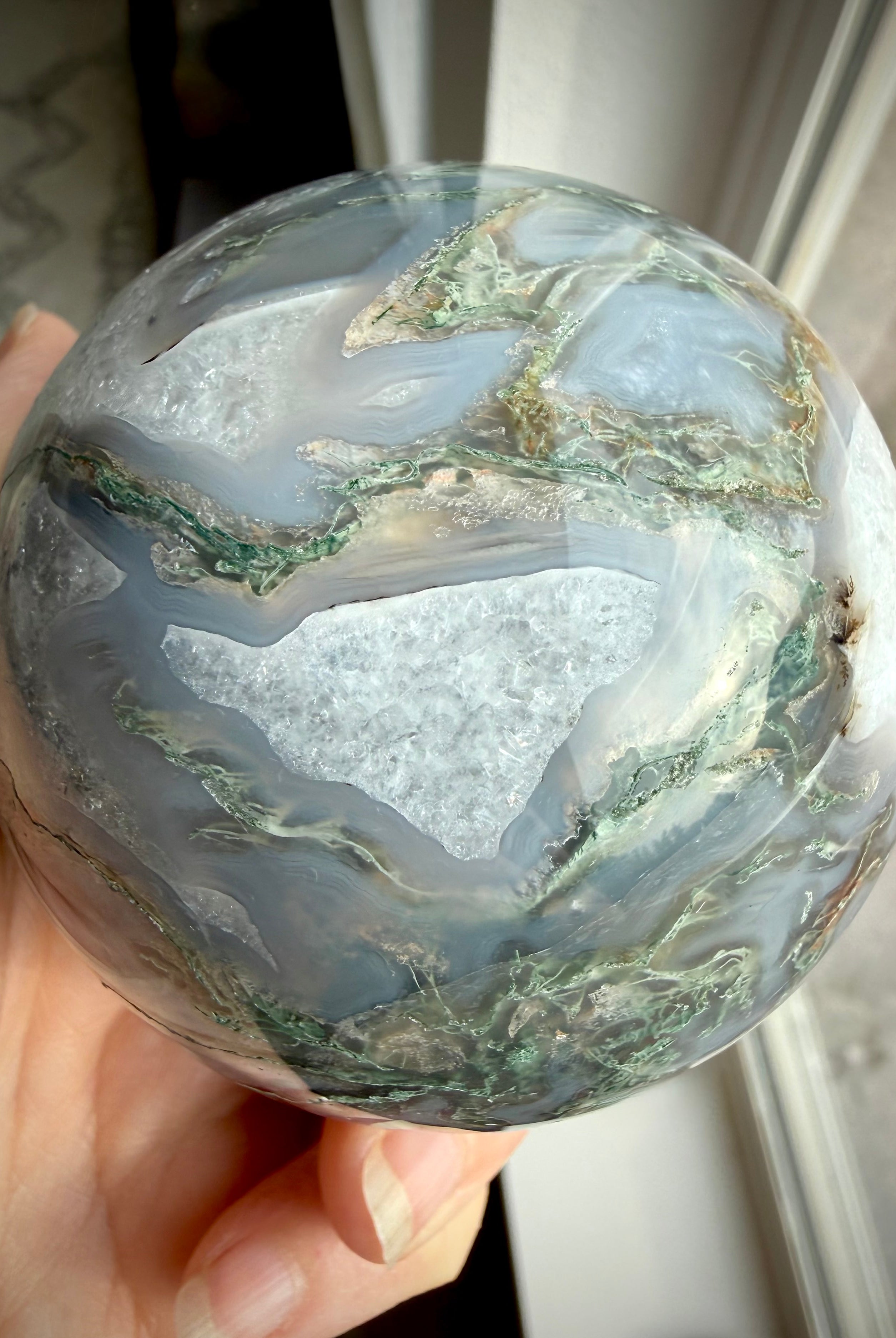 Moss Agate geode sphere showing large sparkling Quartz crystal cave framed by white Quartz and gray chalcedony