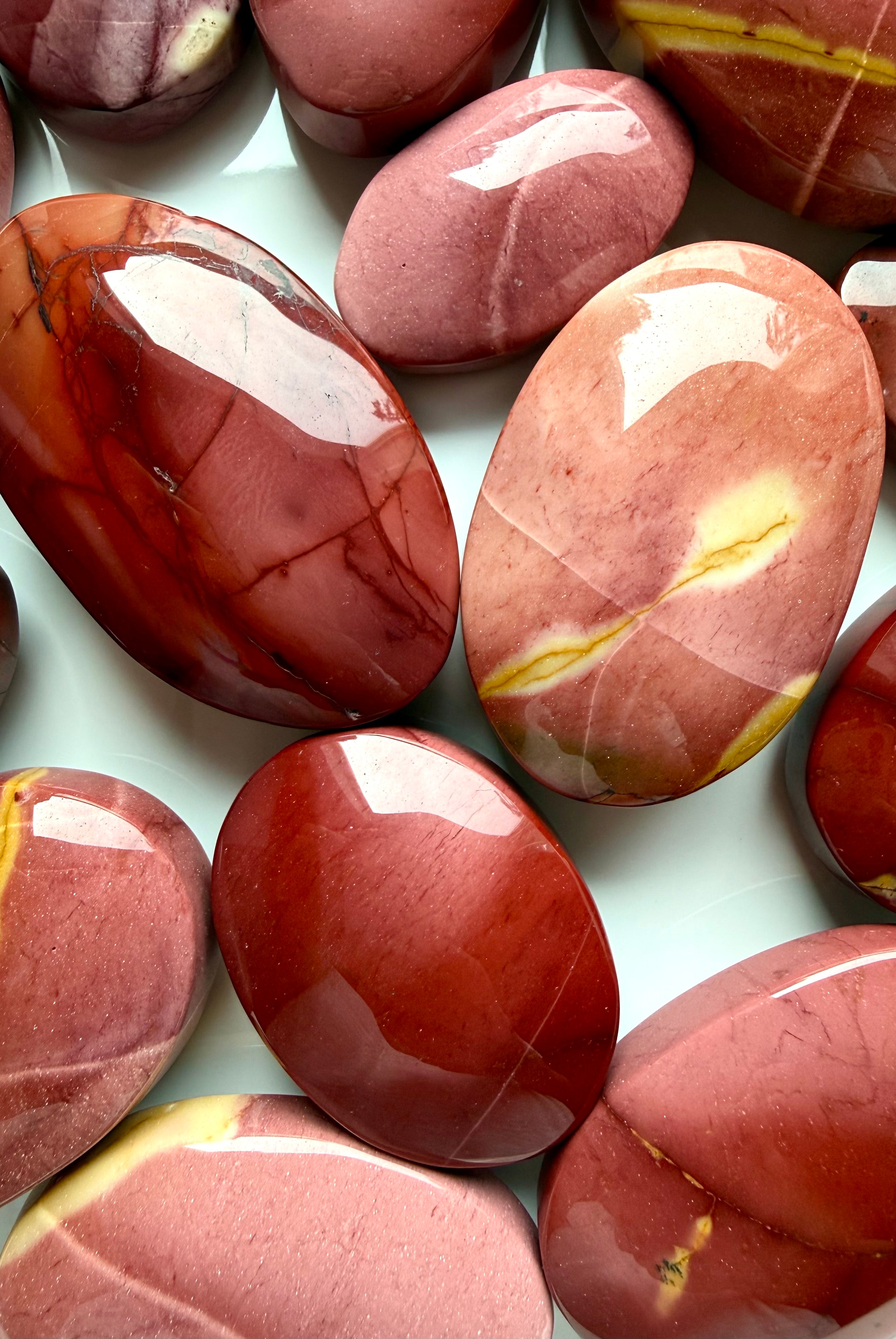 closeup of polished Mookaite Jasper palm stones with warm desert tones and organic banding for emotional stability