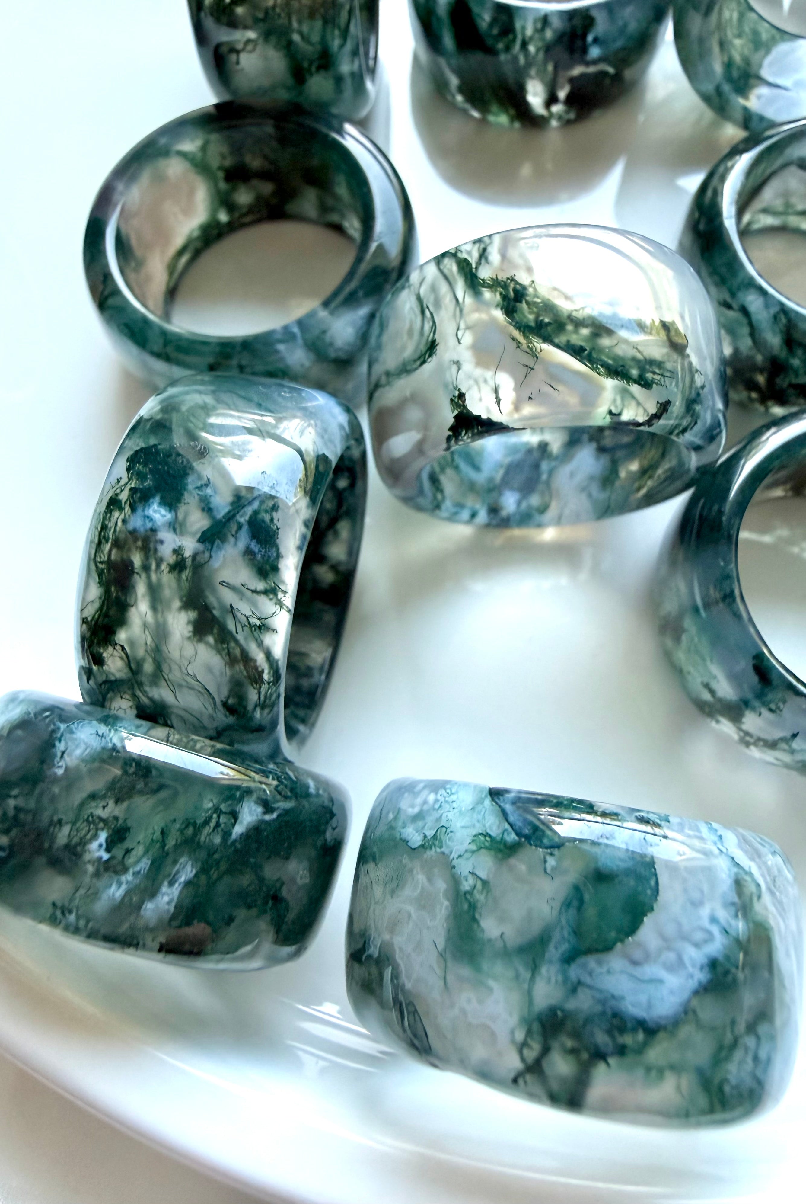 collection of translucent moss agate rings with forest green and gray inclusions, grounding crystal jewelry for heart chakra healing