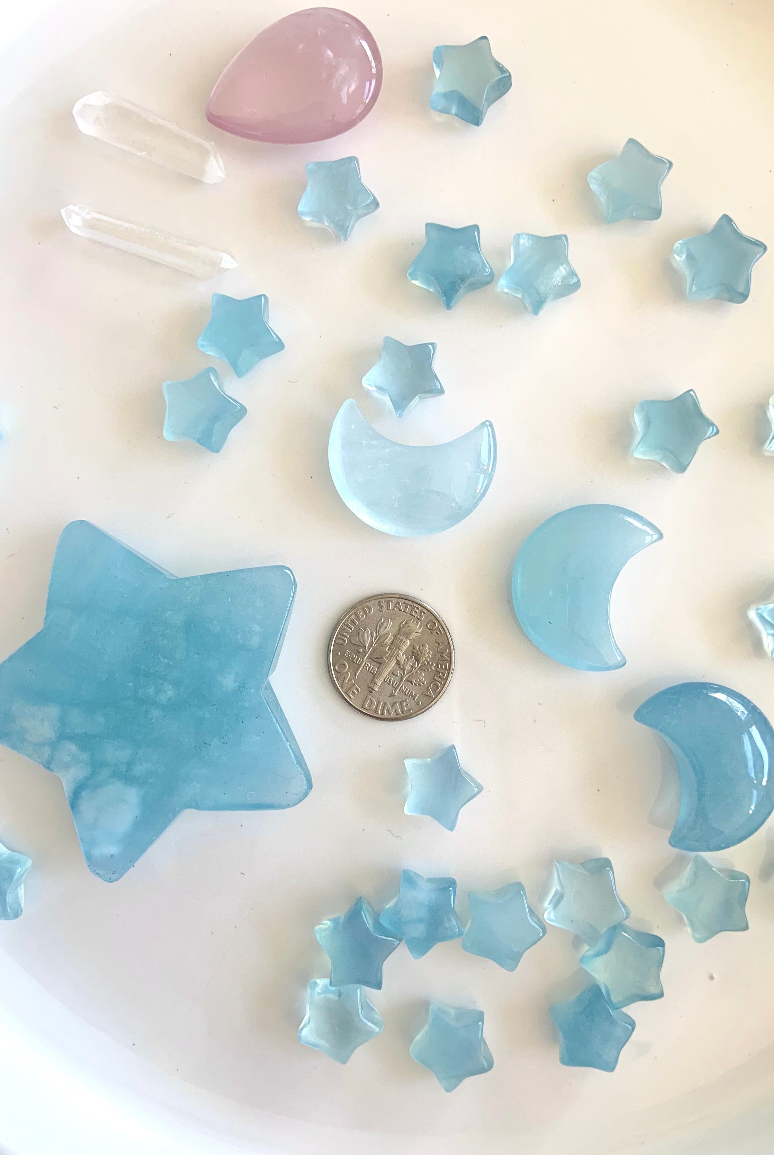 Mini Aquamarine moon and star carvings next to a dime for scale