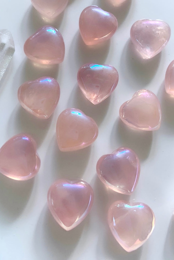 Array of glowing mini angel aura rose quartz hearts on a white background — radiant pink crystals for love, emotional healing & heart chakra energy