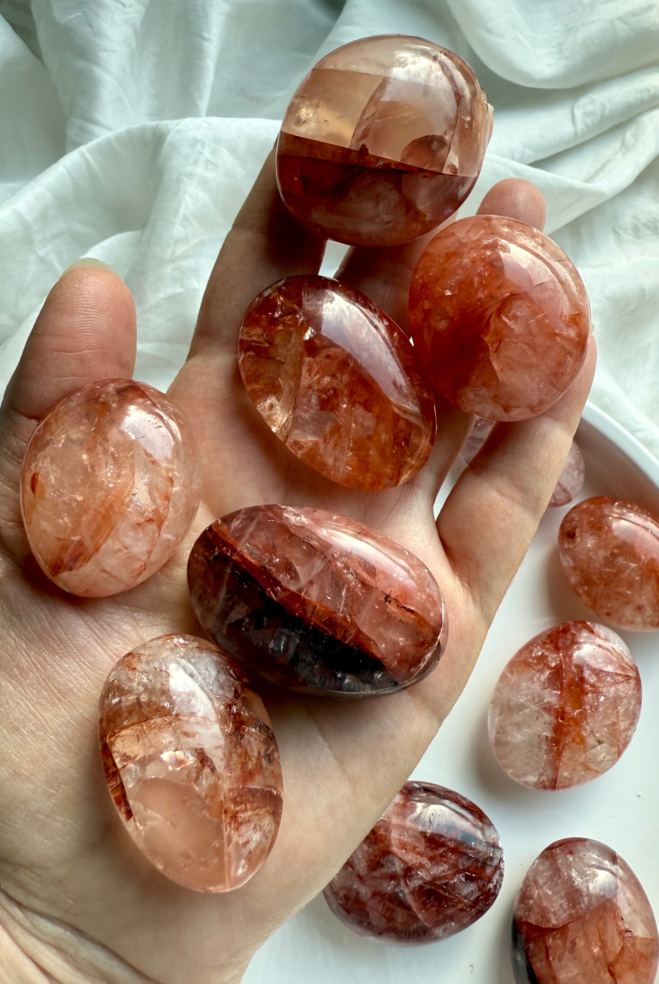 Hand holding polished Fire Quartz palm stones showing natural hematite streaks and grounding energy patterns