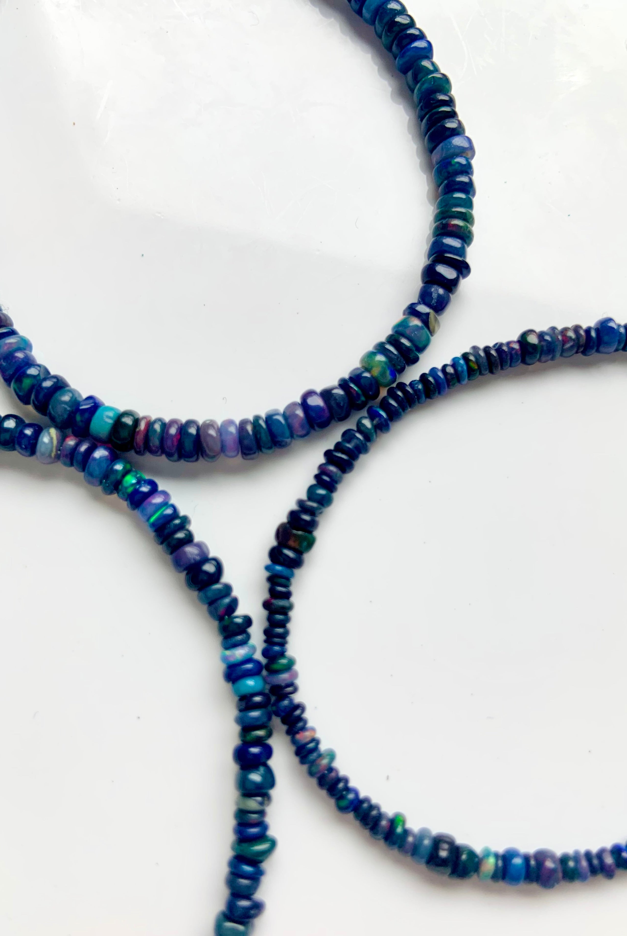 Close-up of three Black Fire Opal bracelets, one in each bead size — 2.9mm, 3.4mm, and 3.8mm — genuine Ethiopian opal jewelry.