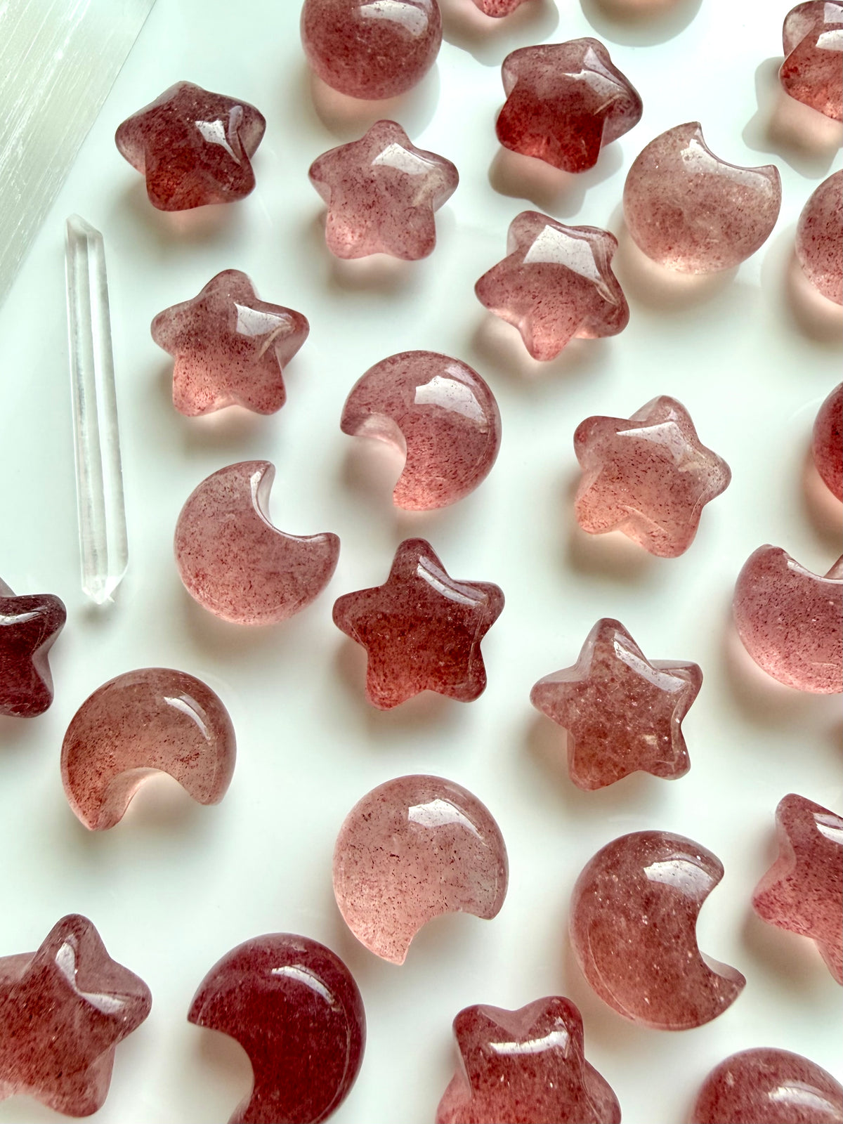 Close-up of Strawberry Quartz moon and star carvings with natural red inclusions, polished surfaces and beautiful color variations