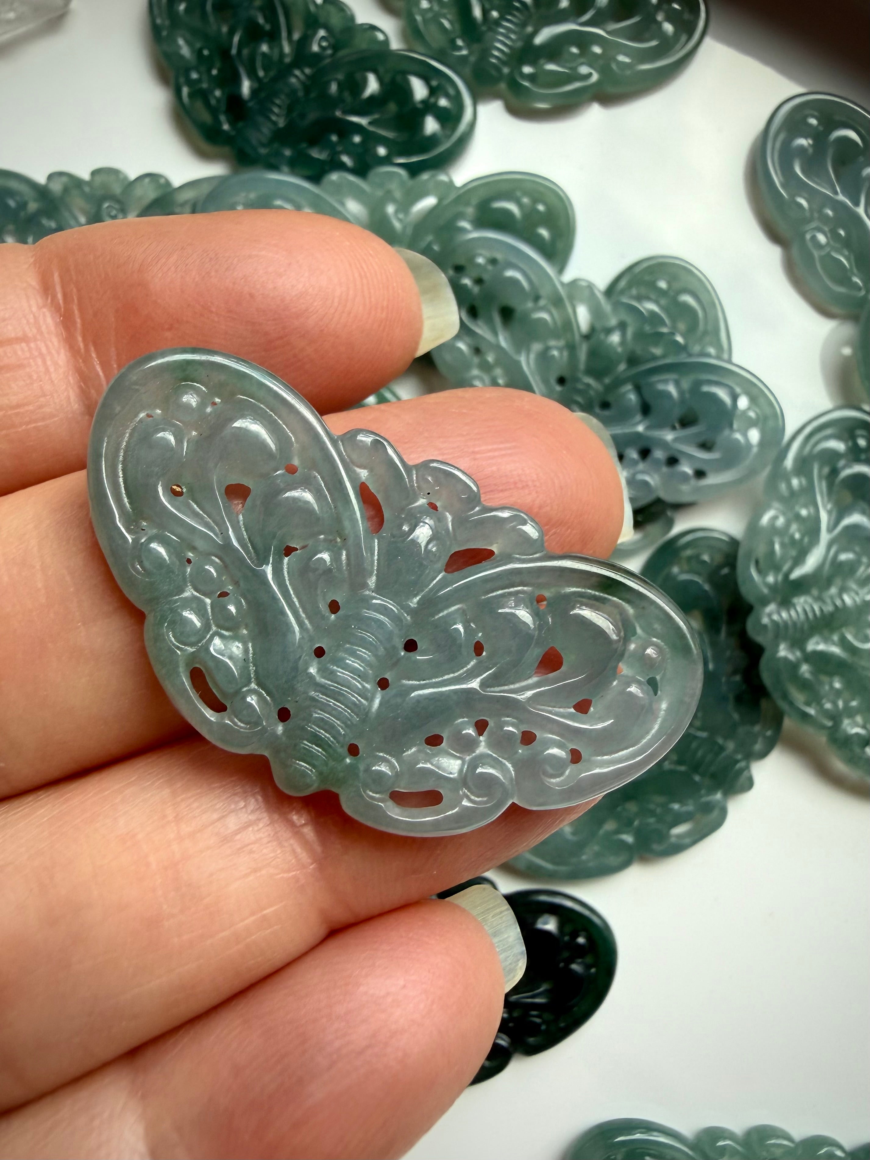 Closeup of Blue Water Jade butterfly carving held in hand showing glossy translucent jadeite