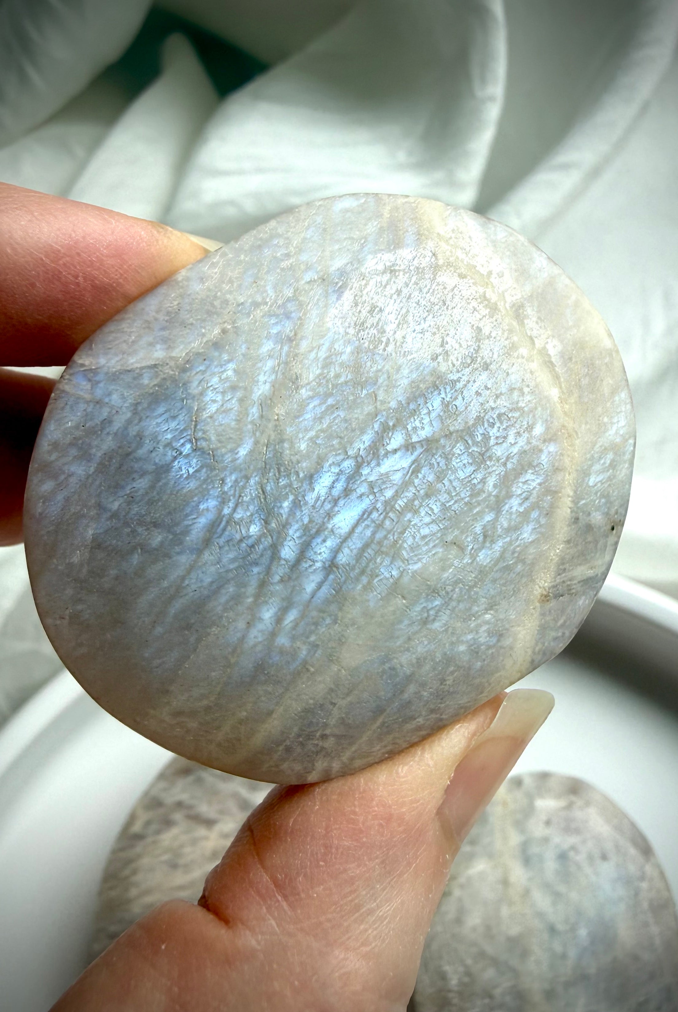 belomorite moonstone palm stone with electric blue flash and natural feldspar shimmer in hand